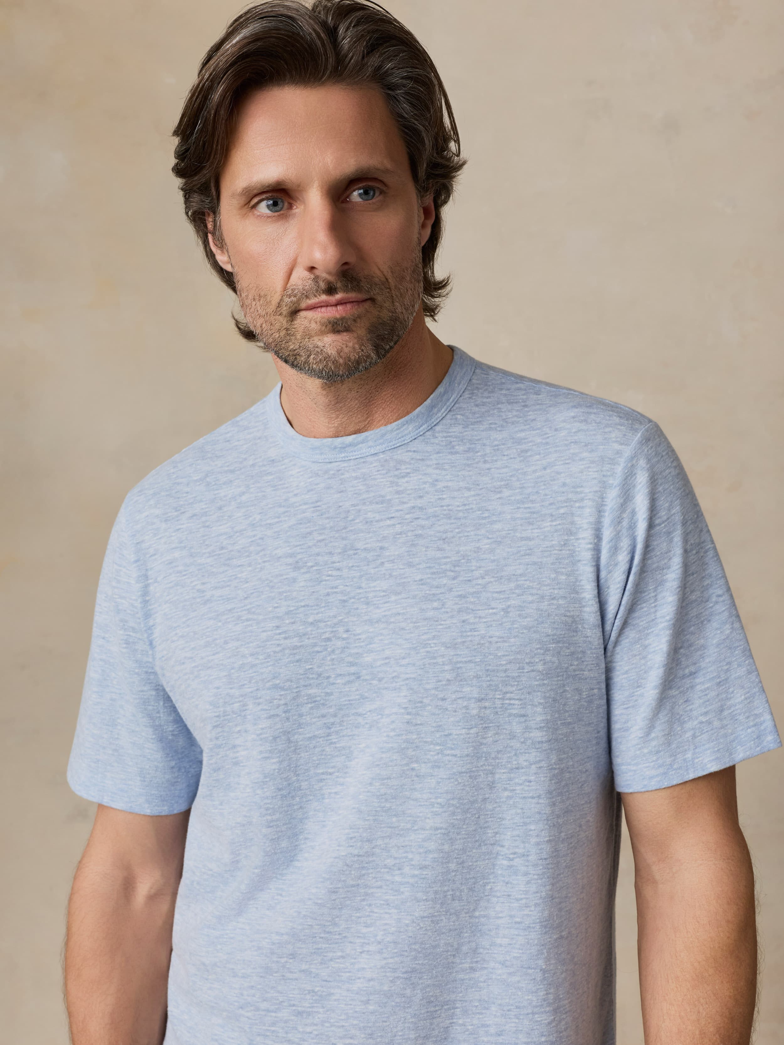 Man wearing a light blue t-shirt against a beige background