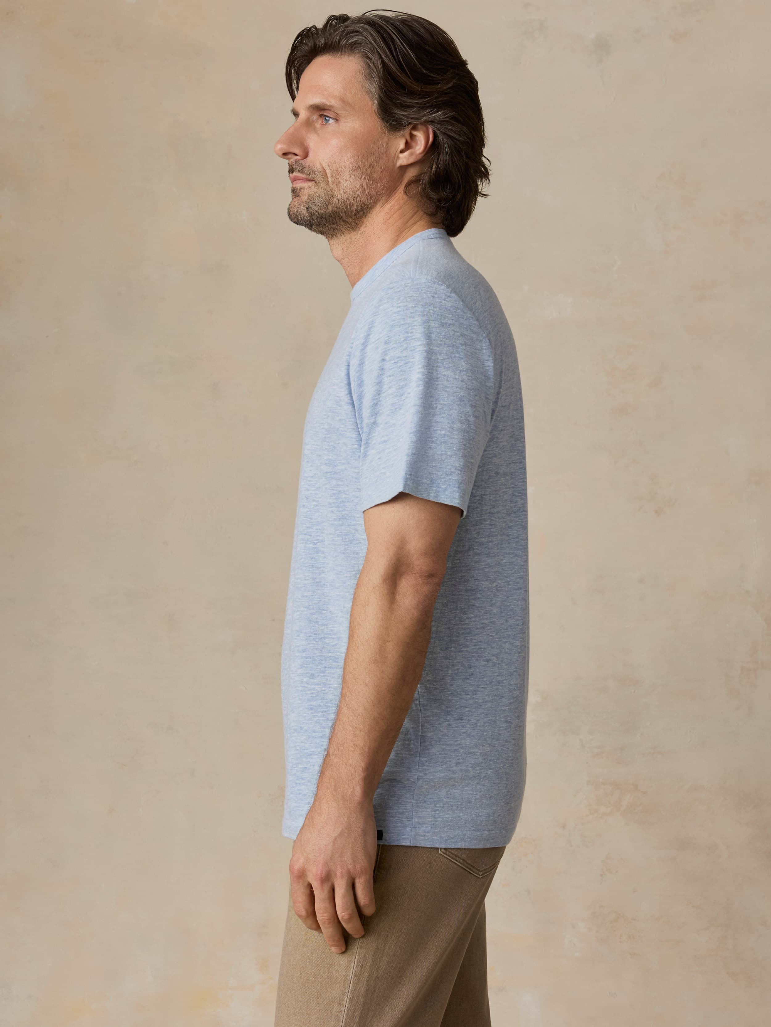 Man wearing a light blue t-shirt against a beige background