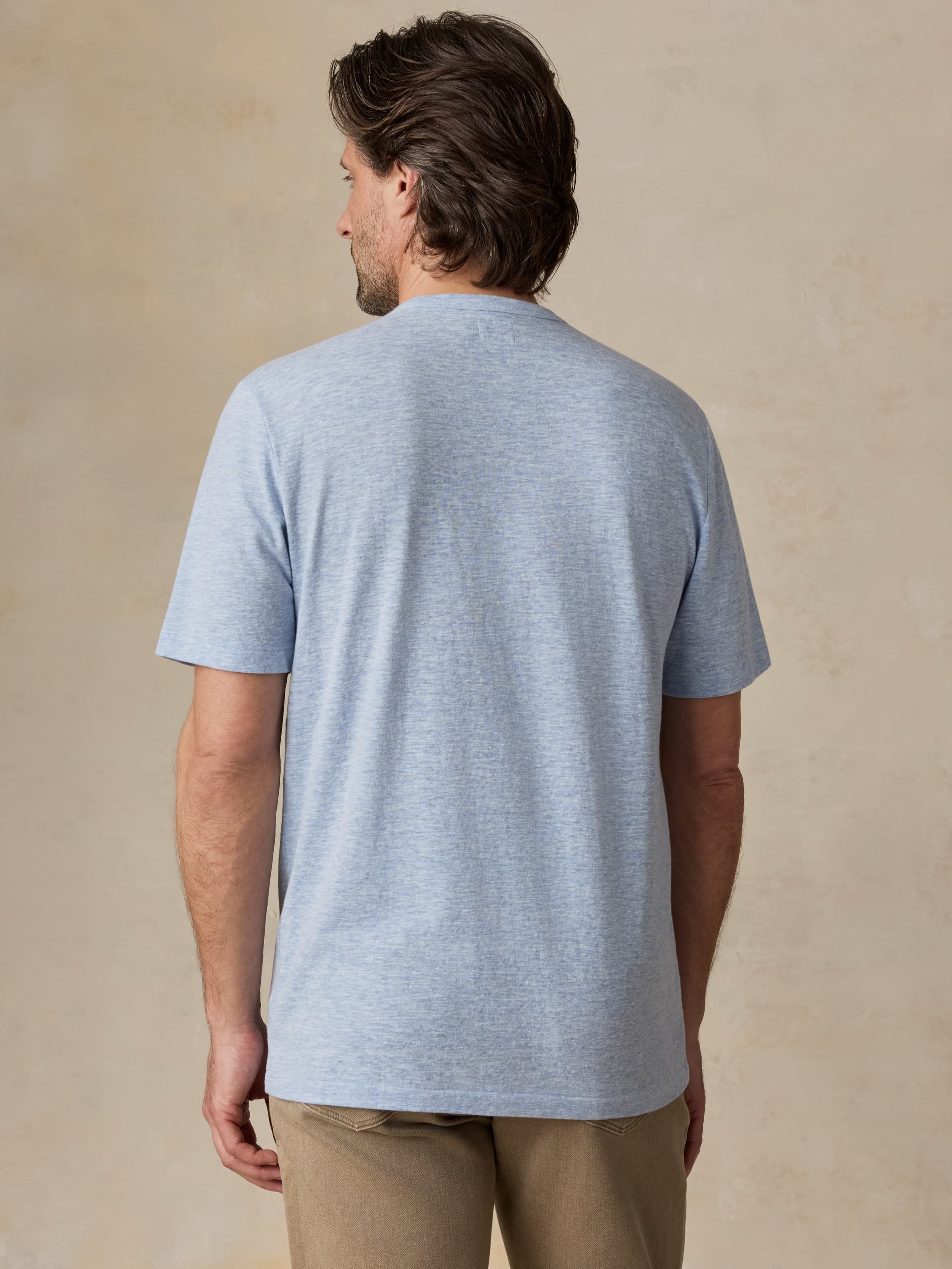 Man wearing a light blue t-shirt against a beige background
