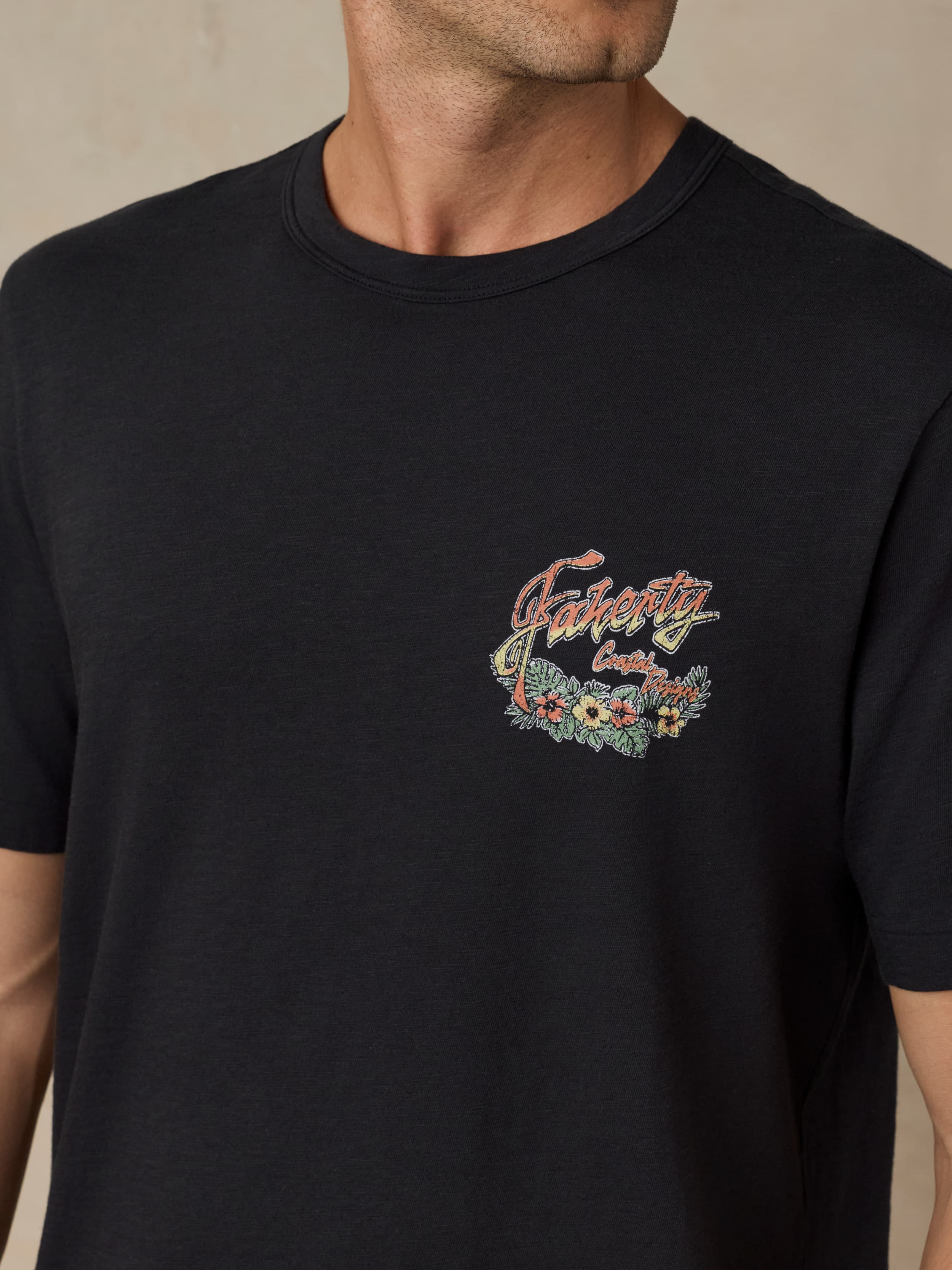 Man wearing a black t-shirt with floral graphic design against a beige background