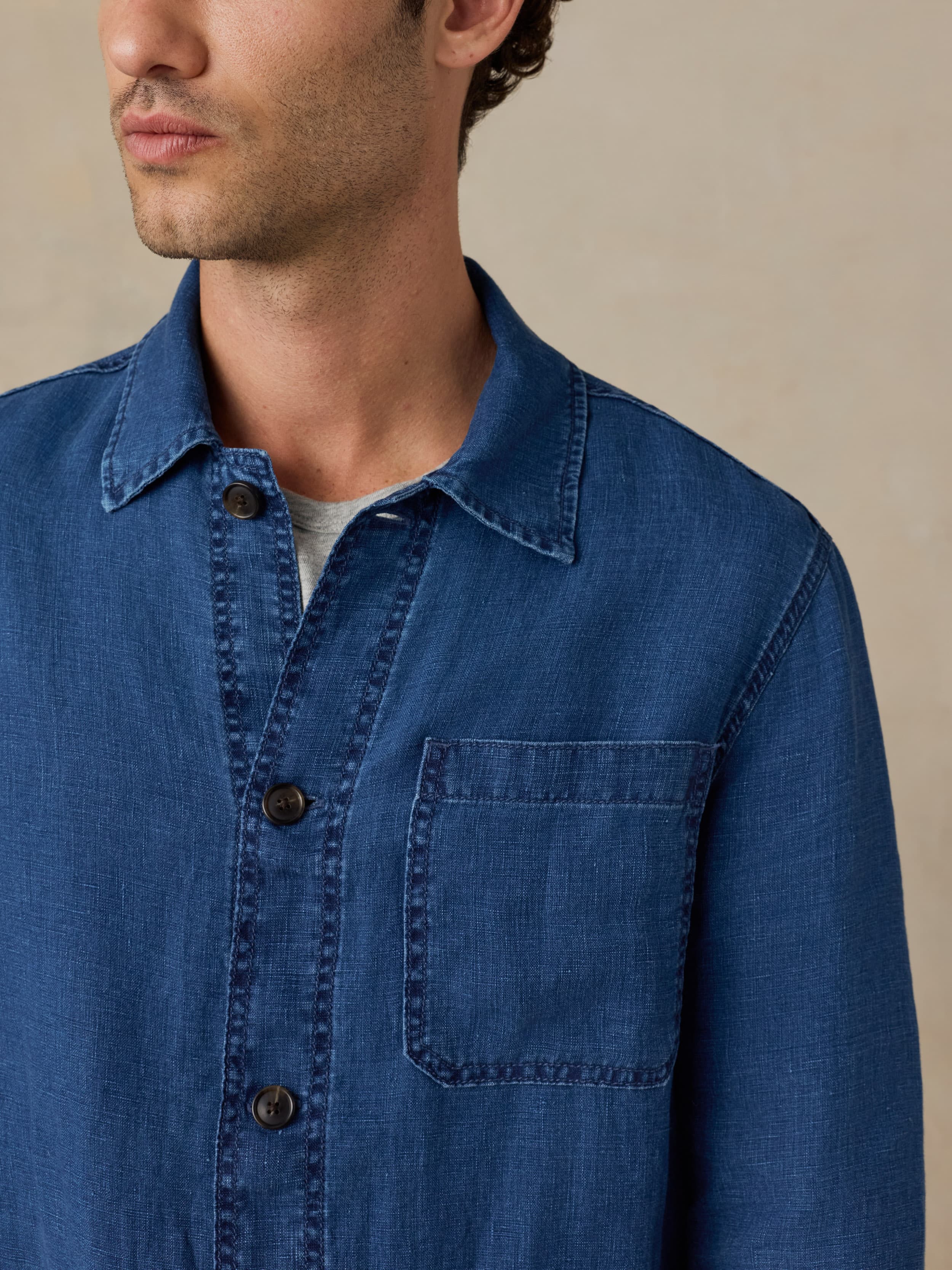 Man wearing a blue denim shirt against a beige background