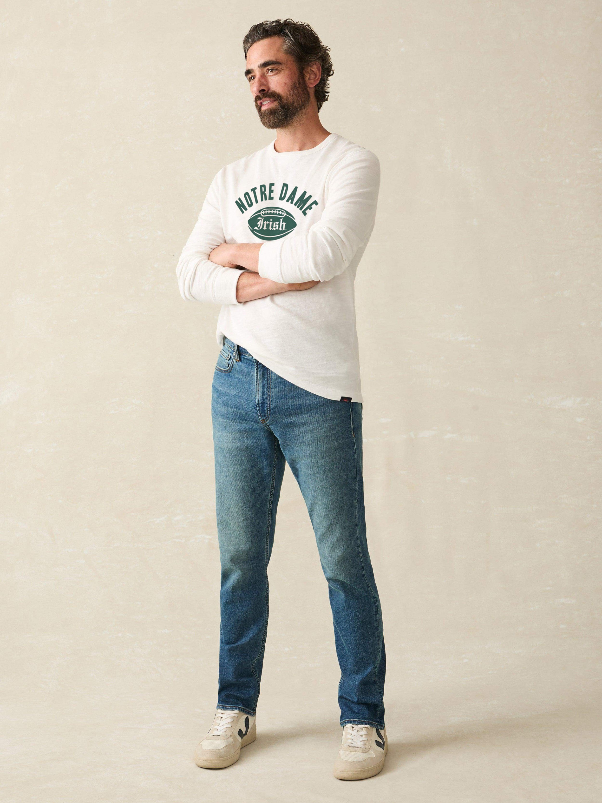 Man wearing a white long-sleeve shirt with 'Notre Dame Football' graphic on a beige background