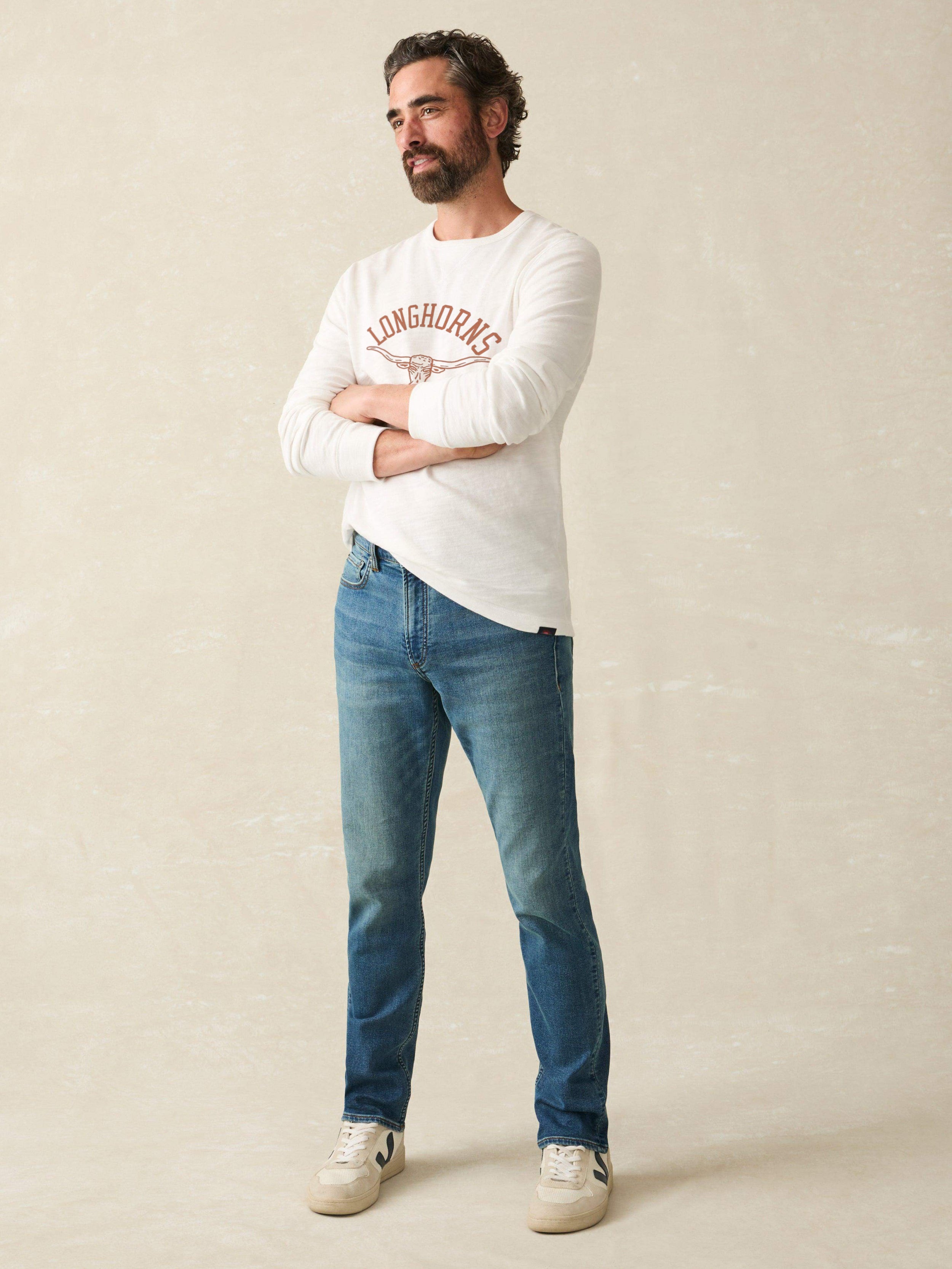 Man wearing a white long-sleeve shirt with University of Texas graphic at the center chest against a beige background