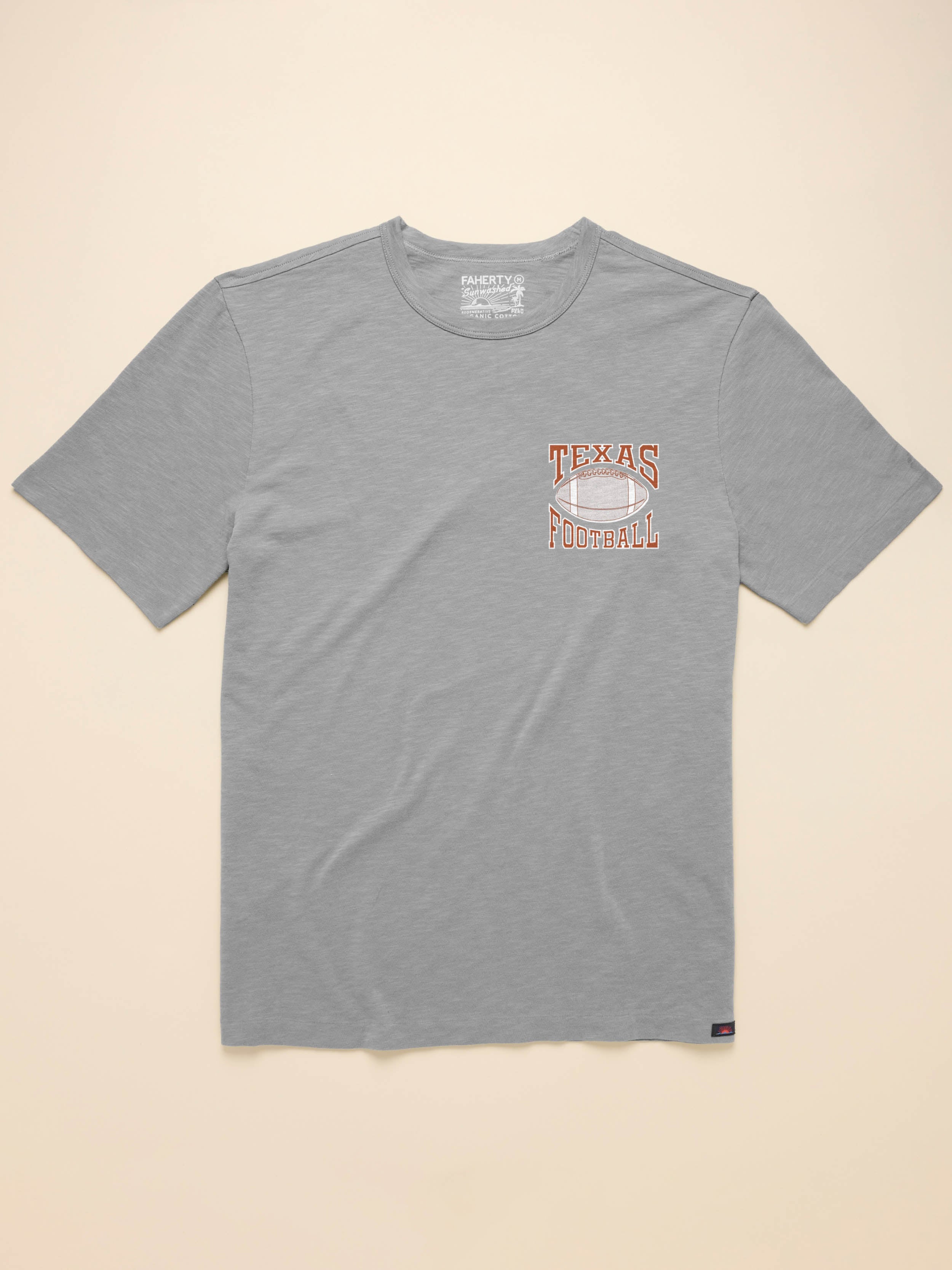 Grey short sleeve t-shirt with UT Austin graphic on the left chest against a beige background