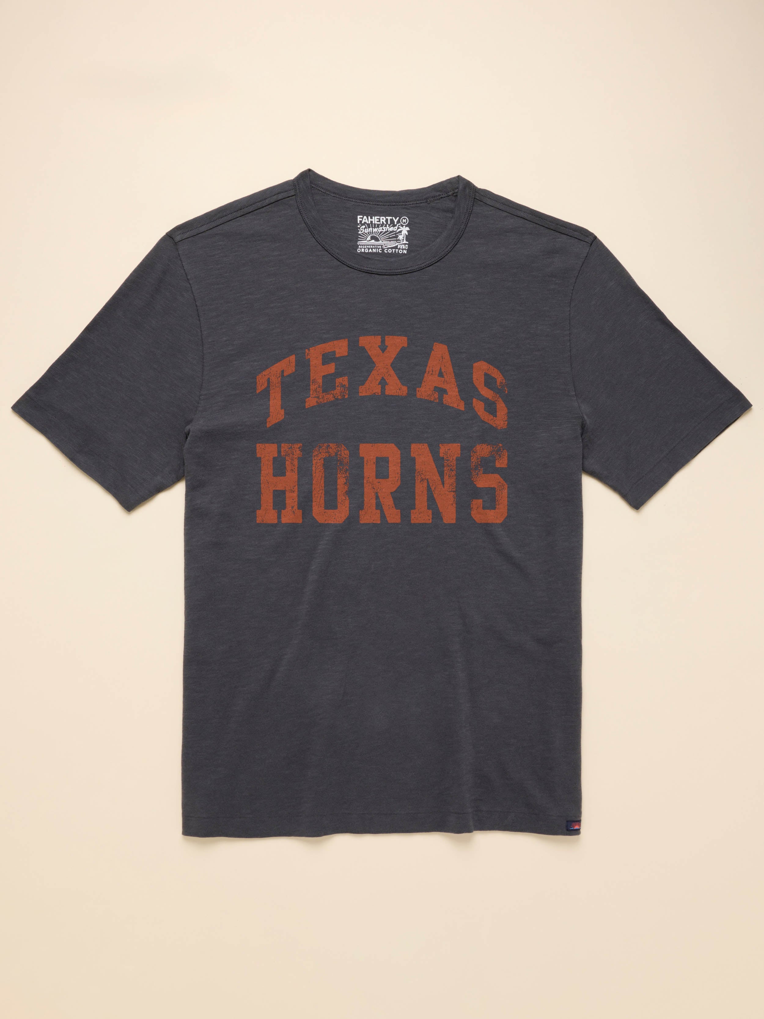 Grey short sleeve t-shirt with UT Austin graphic logo on the center front against a beige background