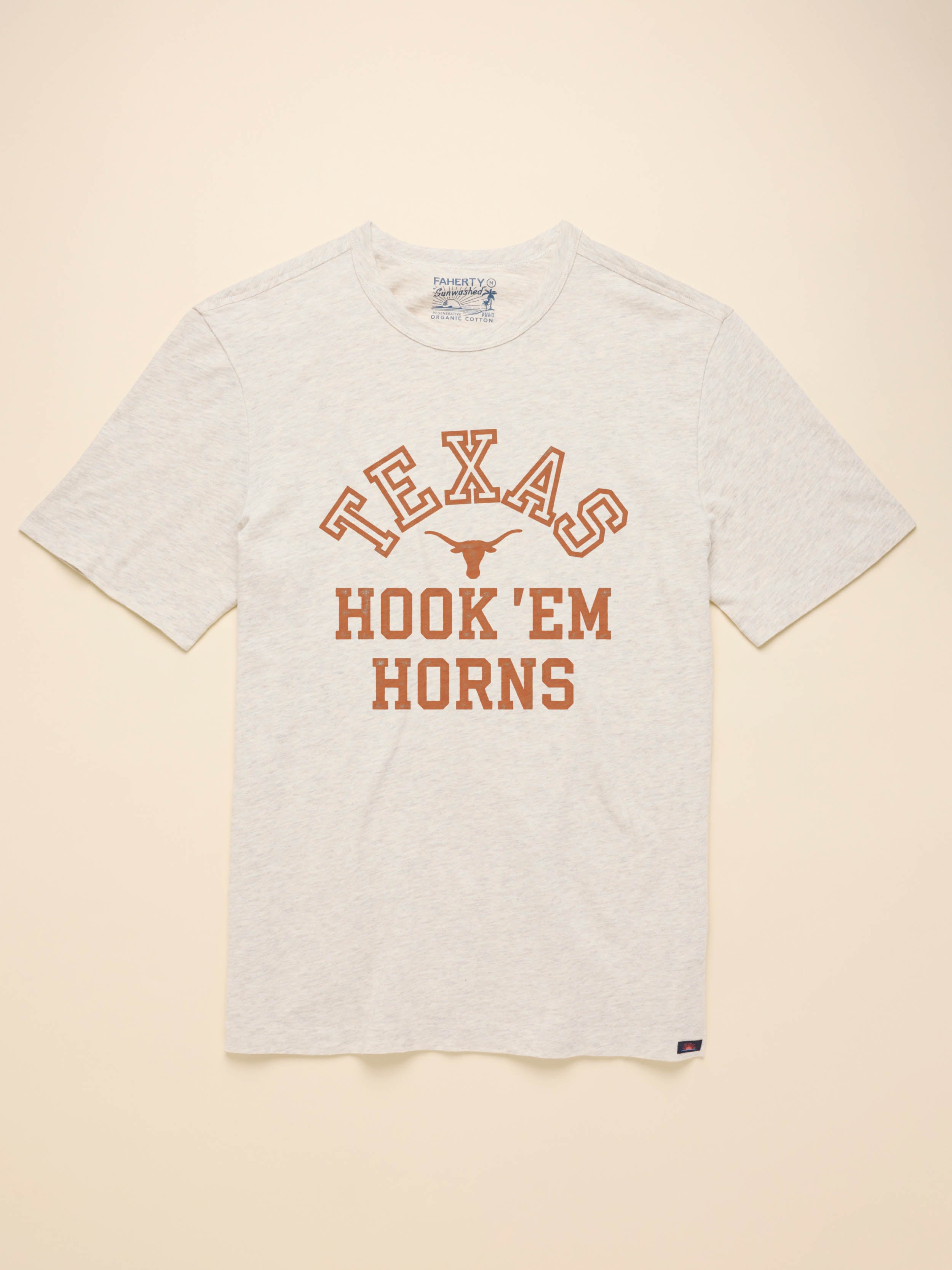 Light grey short sleeeve t-shirt with UT Austing graphic on the center front against a beige background
