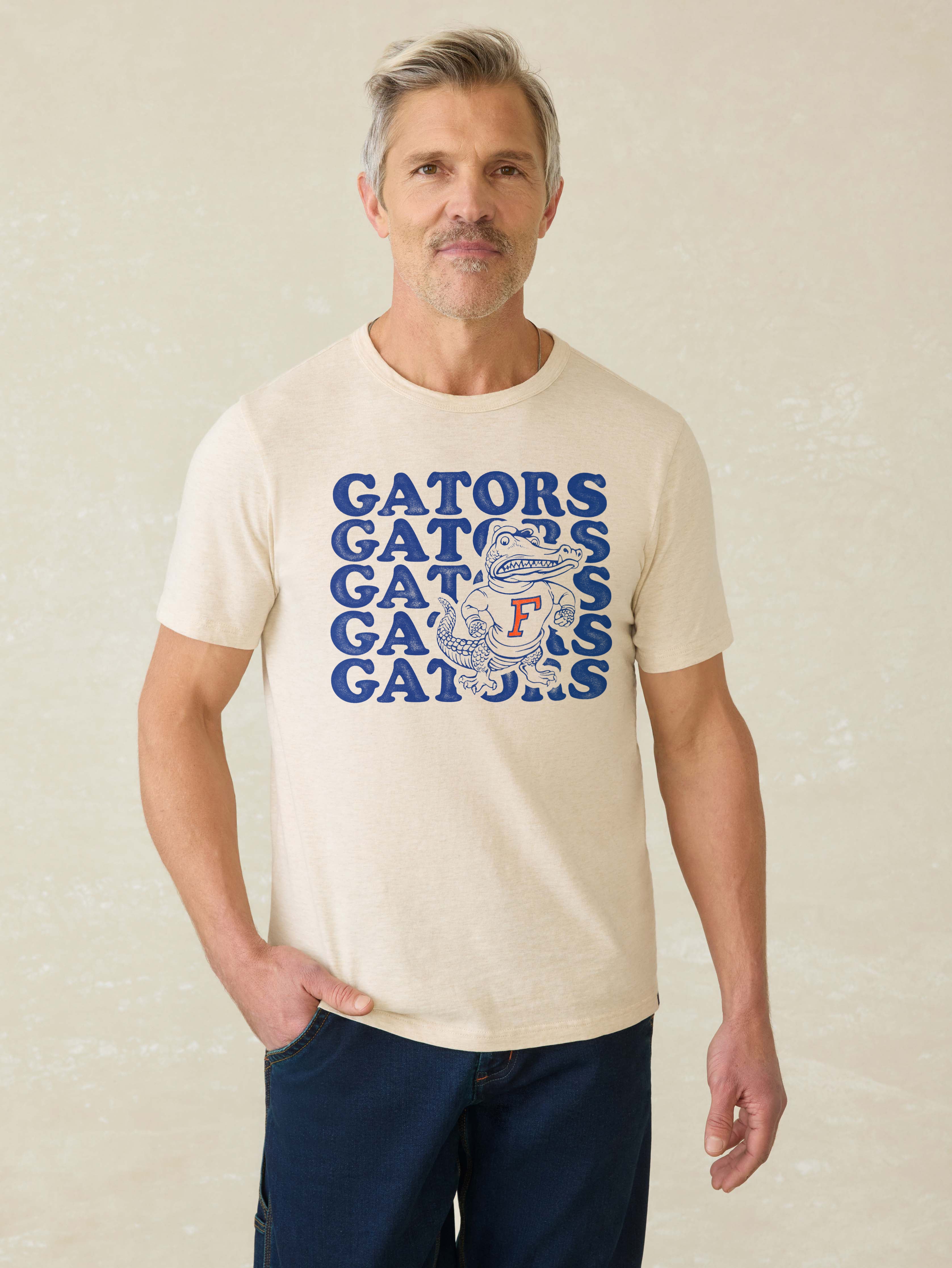 Man wearing a white short-sleeve t-shirt with University of Florida graphic at the center front against a beige background