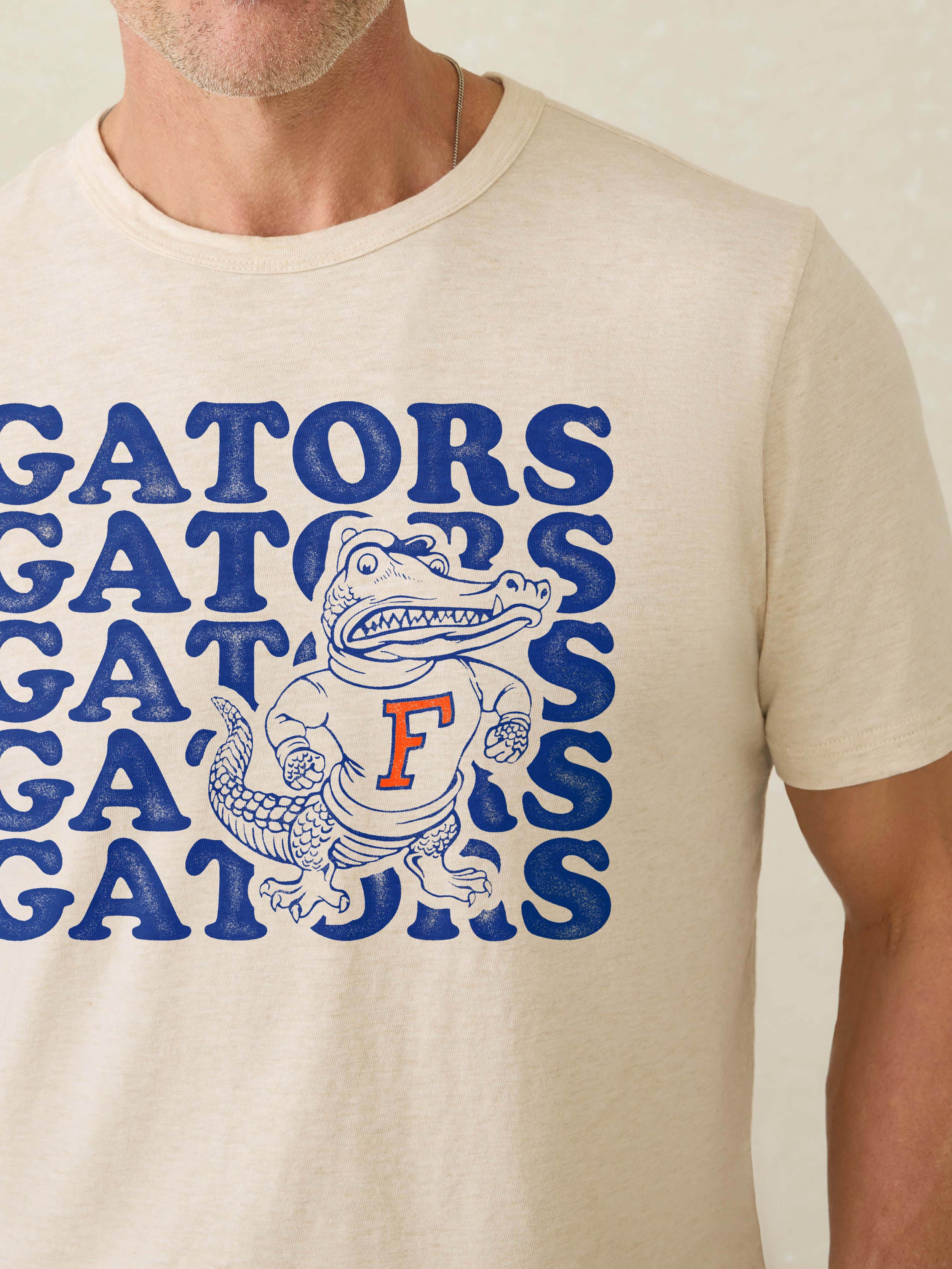 Man wearing a white short-sleeve t-shirt with University of Florida graphic at the center front against a beige background