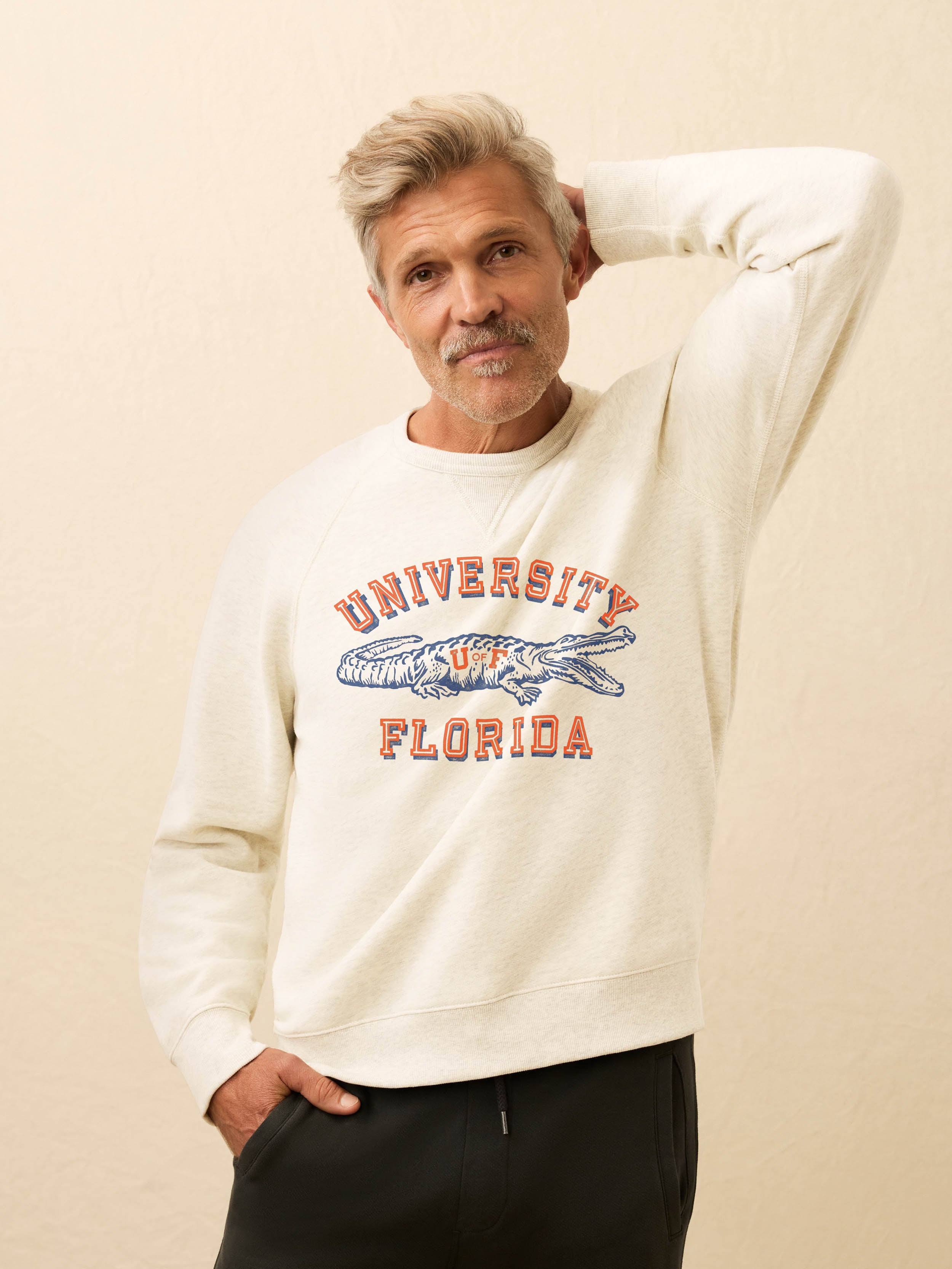 Man wearing a white crewneck sweatshirt with Florida graphic on the chest against a beige background