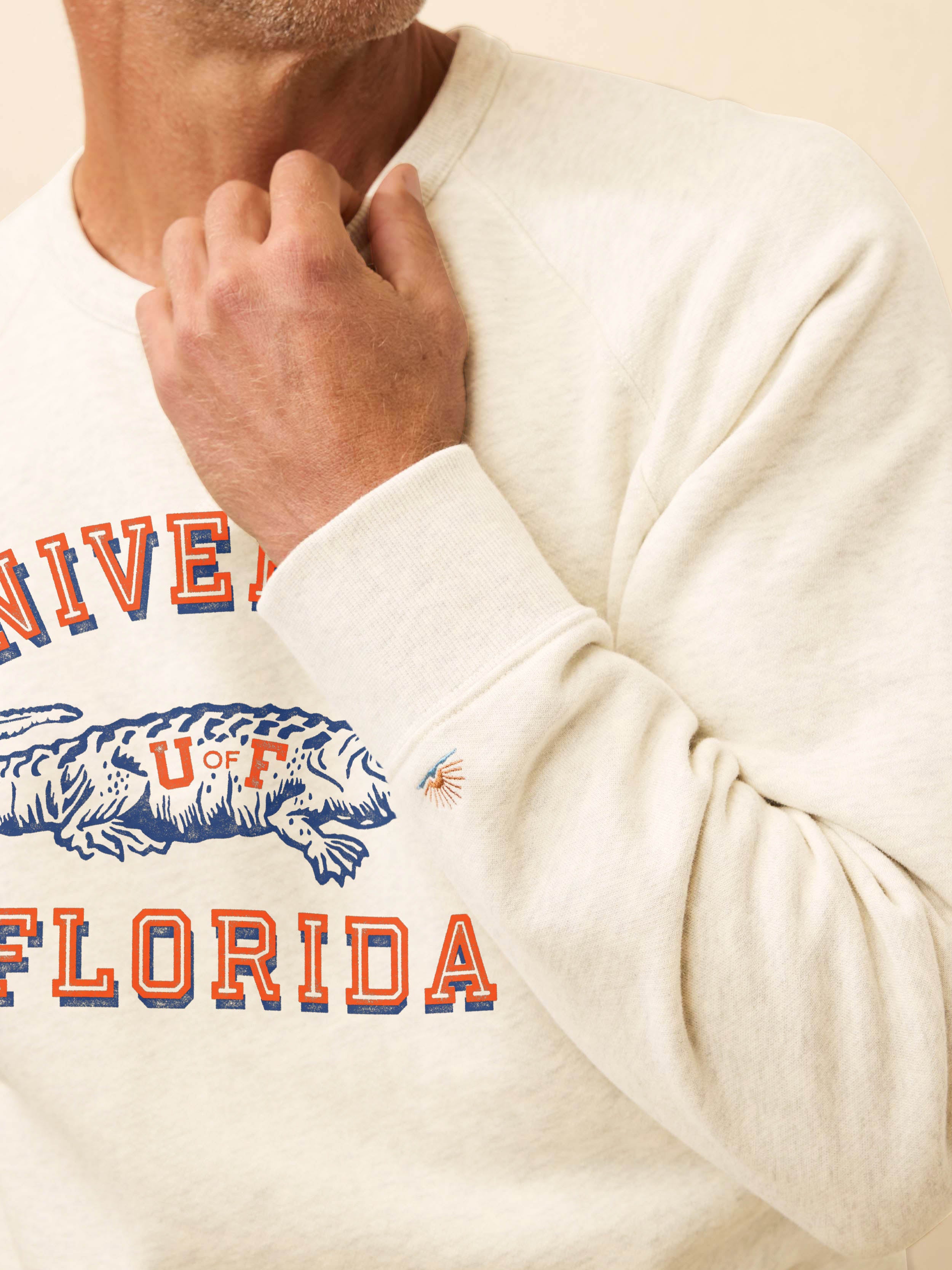 Man wearing a white crewneck sweatshirt with Florida graphic on the chest against a beige background