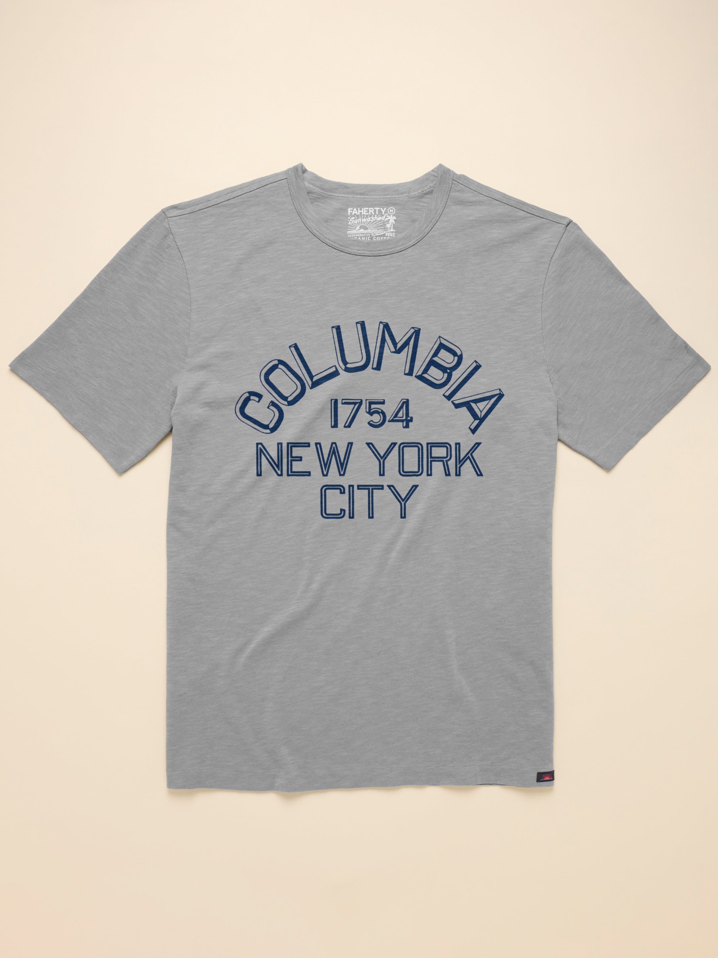 Grey short sleeve t-shirt with Columbia graphic on the center front against a beige background