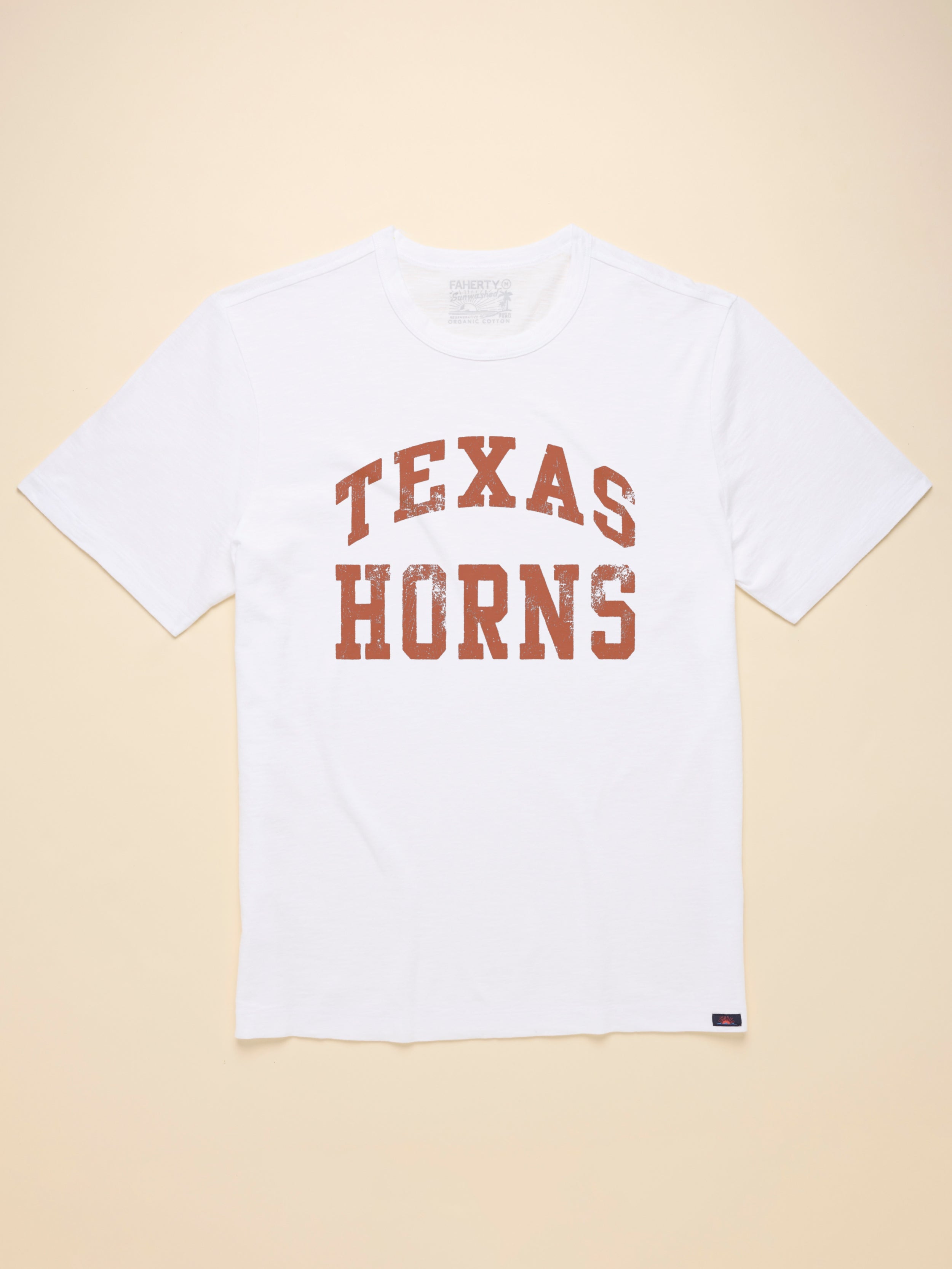 Man wearing a white short sleeve t-shirt with UT Austin graphic at the center front against a beige background