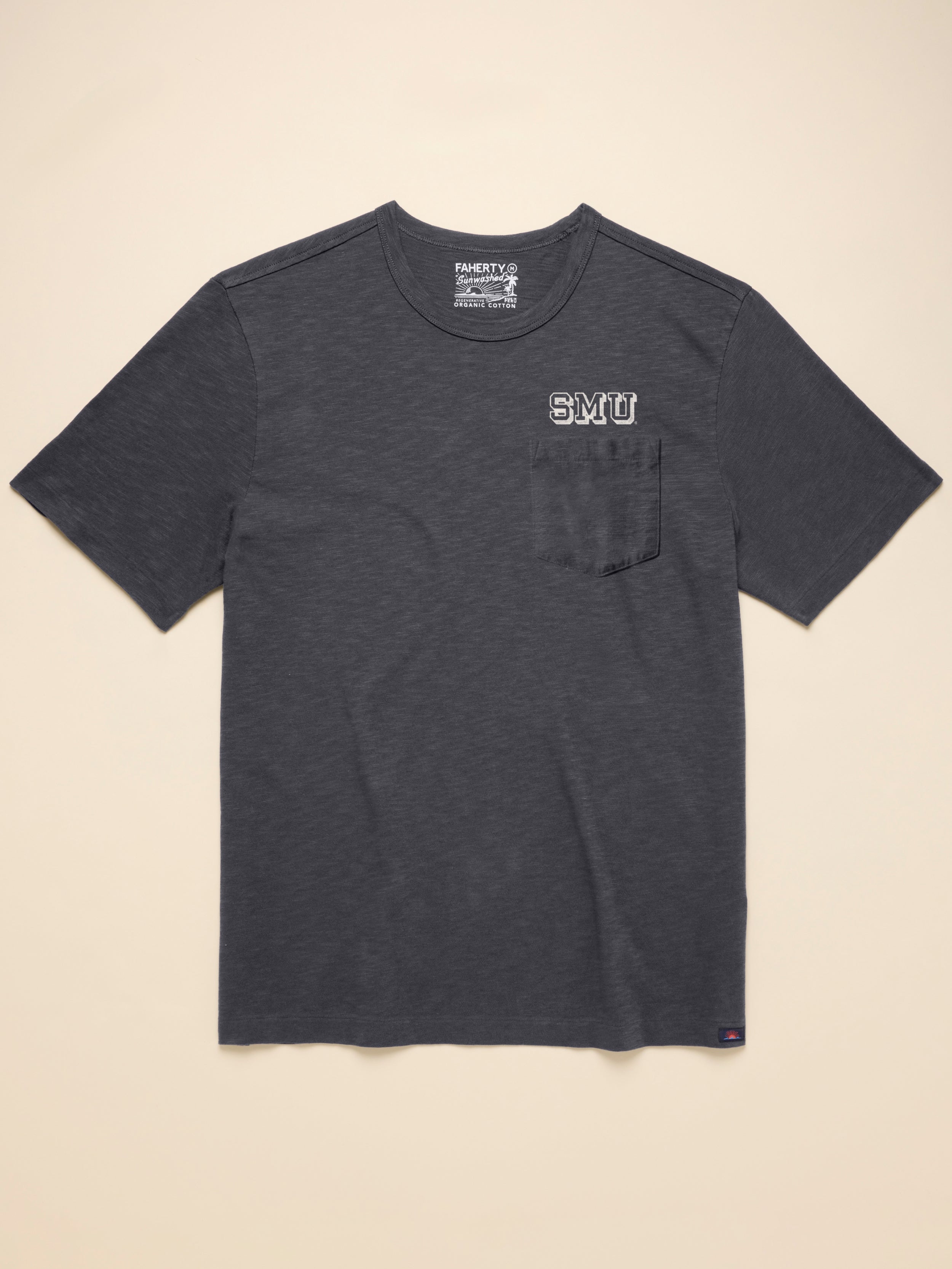 Dark grey short sleeve t-shirt with SMU graphic at left chest pocket against a beige background