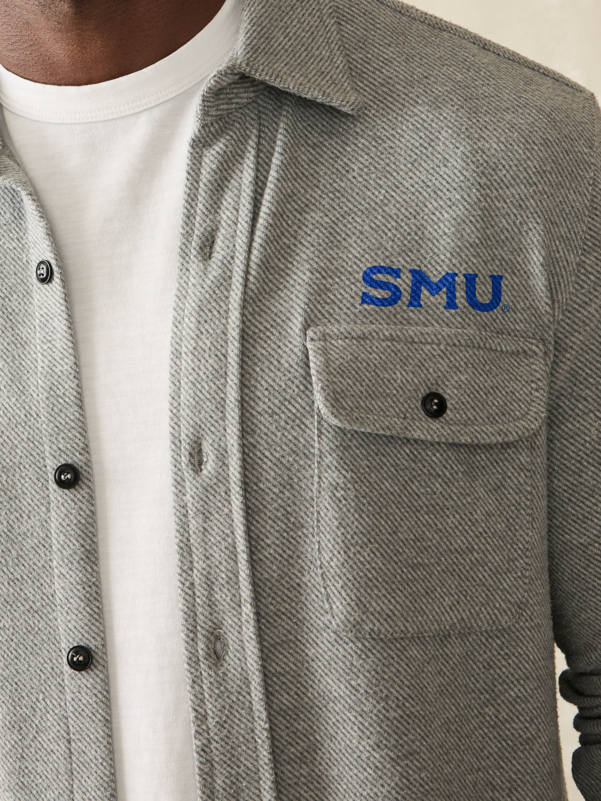 Man wearing a grey shirt with SMU graphic on front chest and shoulder