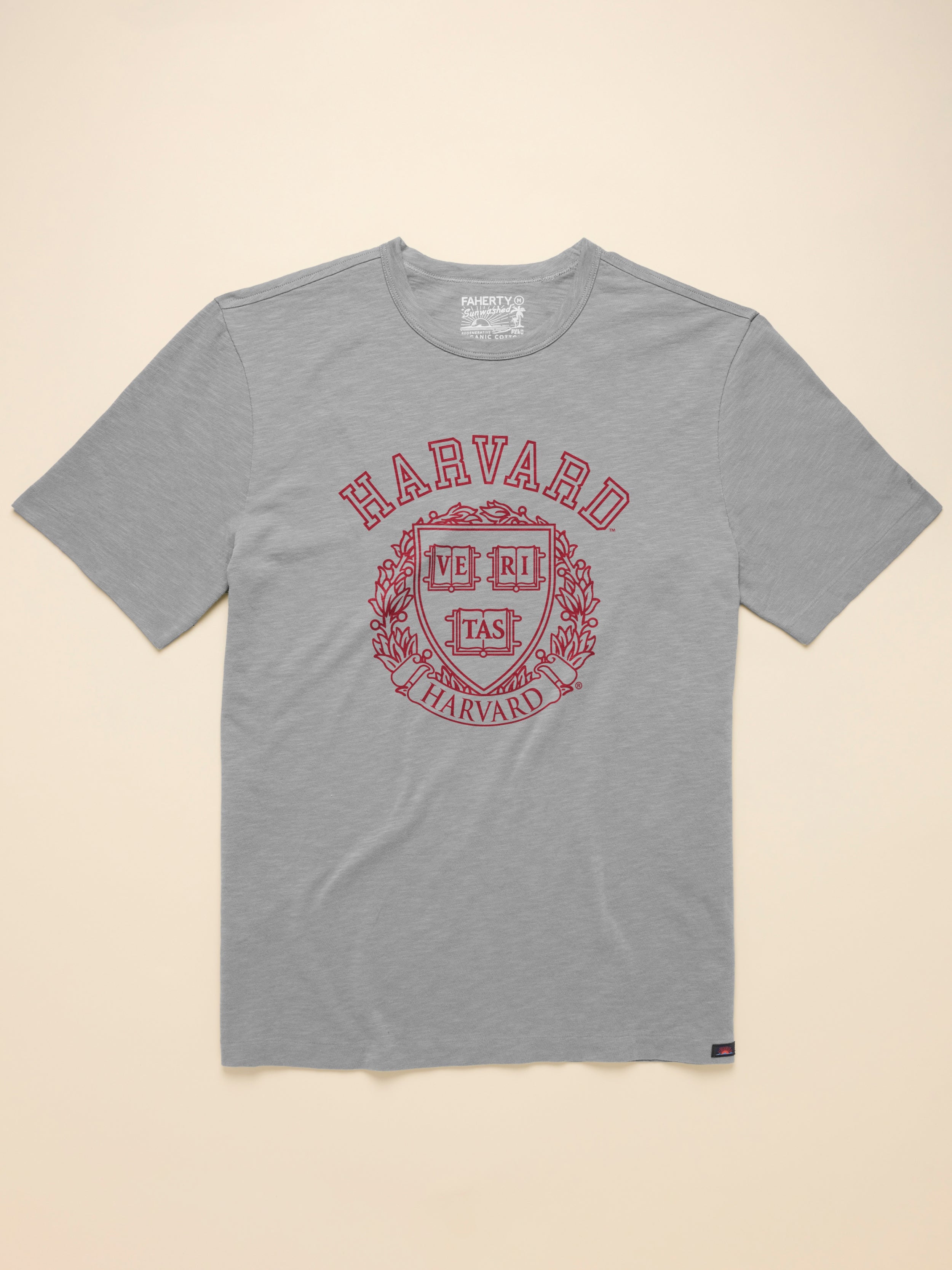 Grey t shirt with Harvard graphic on the front against a beige background