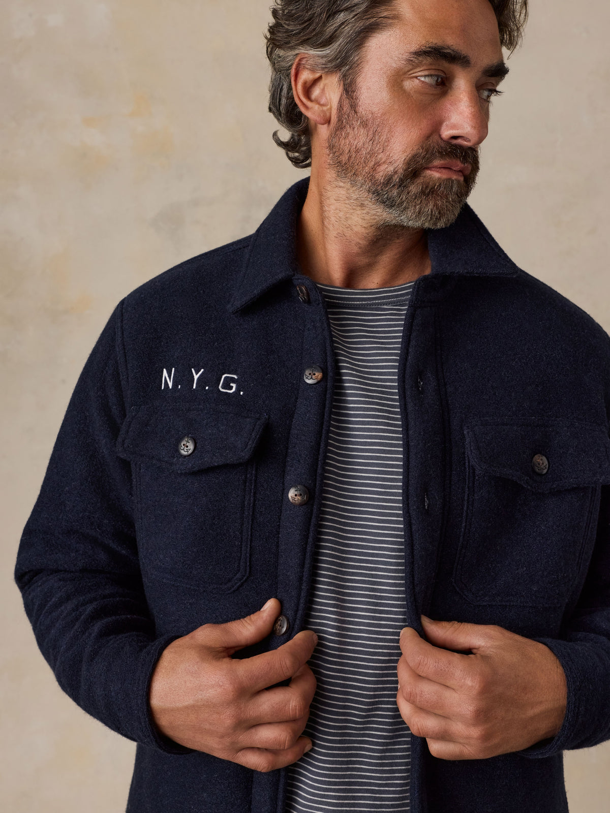 A man wearing a blue NY Giants jacket over a striped tee, image 4 of 5