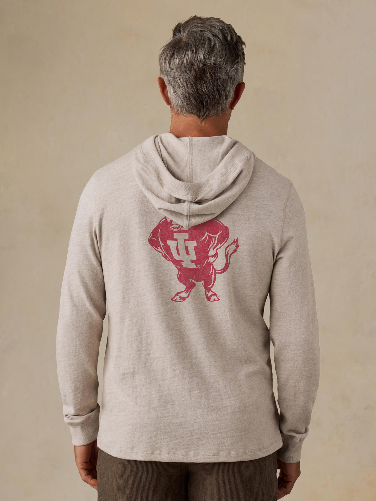 A man viewed from behind wearing a grey Indiana University hoodie and brown shorts, image 2 of 2