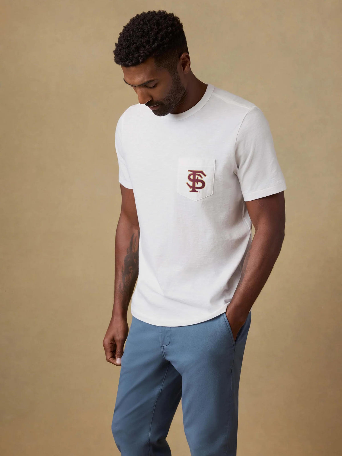 A man wearing a white Florida State pocket tee and blue pants, image 1 of 2