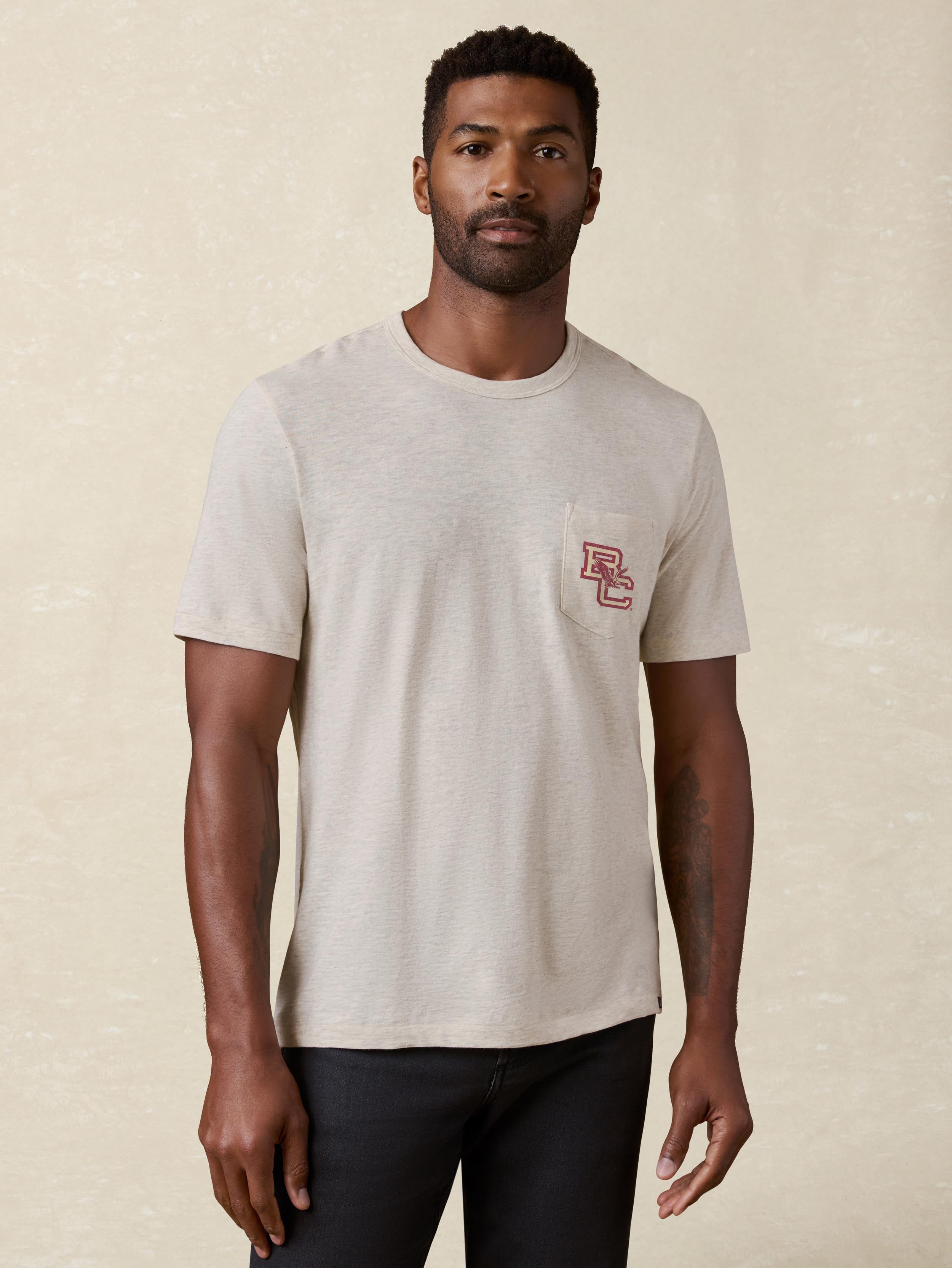 A man wearing a grey Boston College pocket tee and black pants