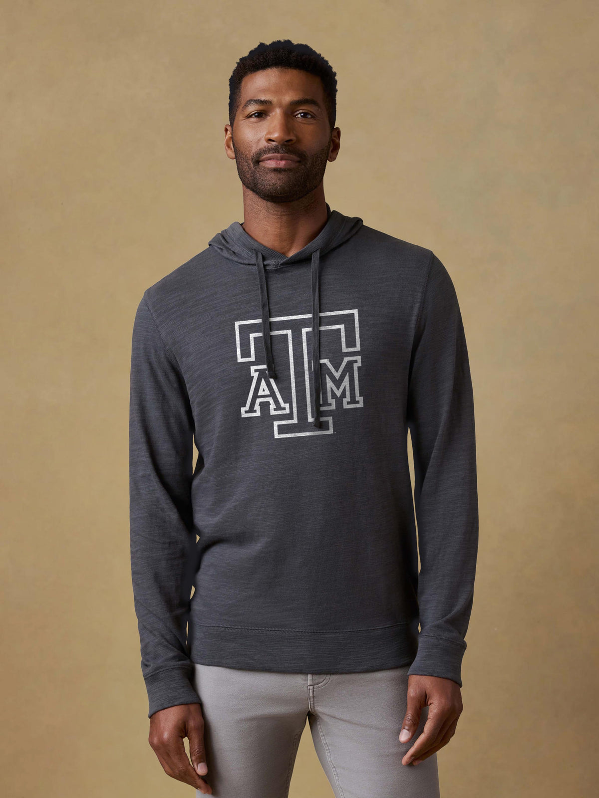 A man wearing a grey Texas A&M hoodie and light grey pants, image 1 of 1