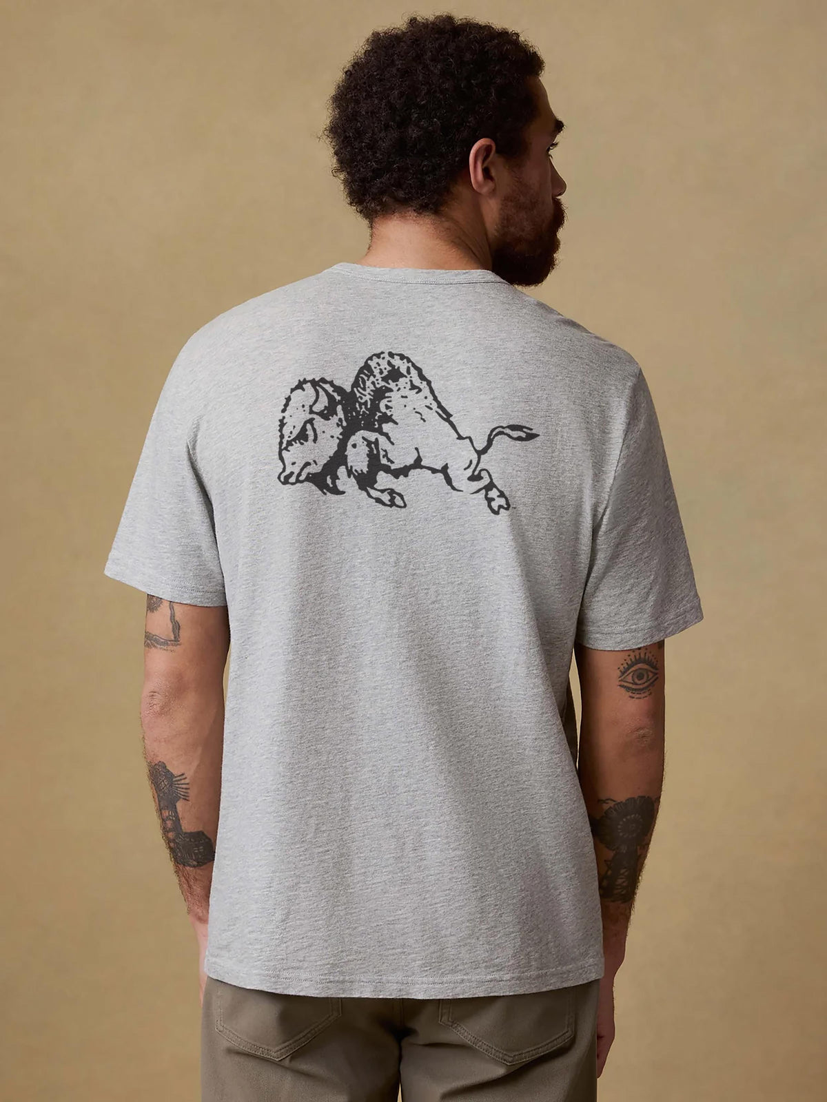 A man viewed from behind wearing a grey CU Boulder tee and brown pants, image 2 of 2