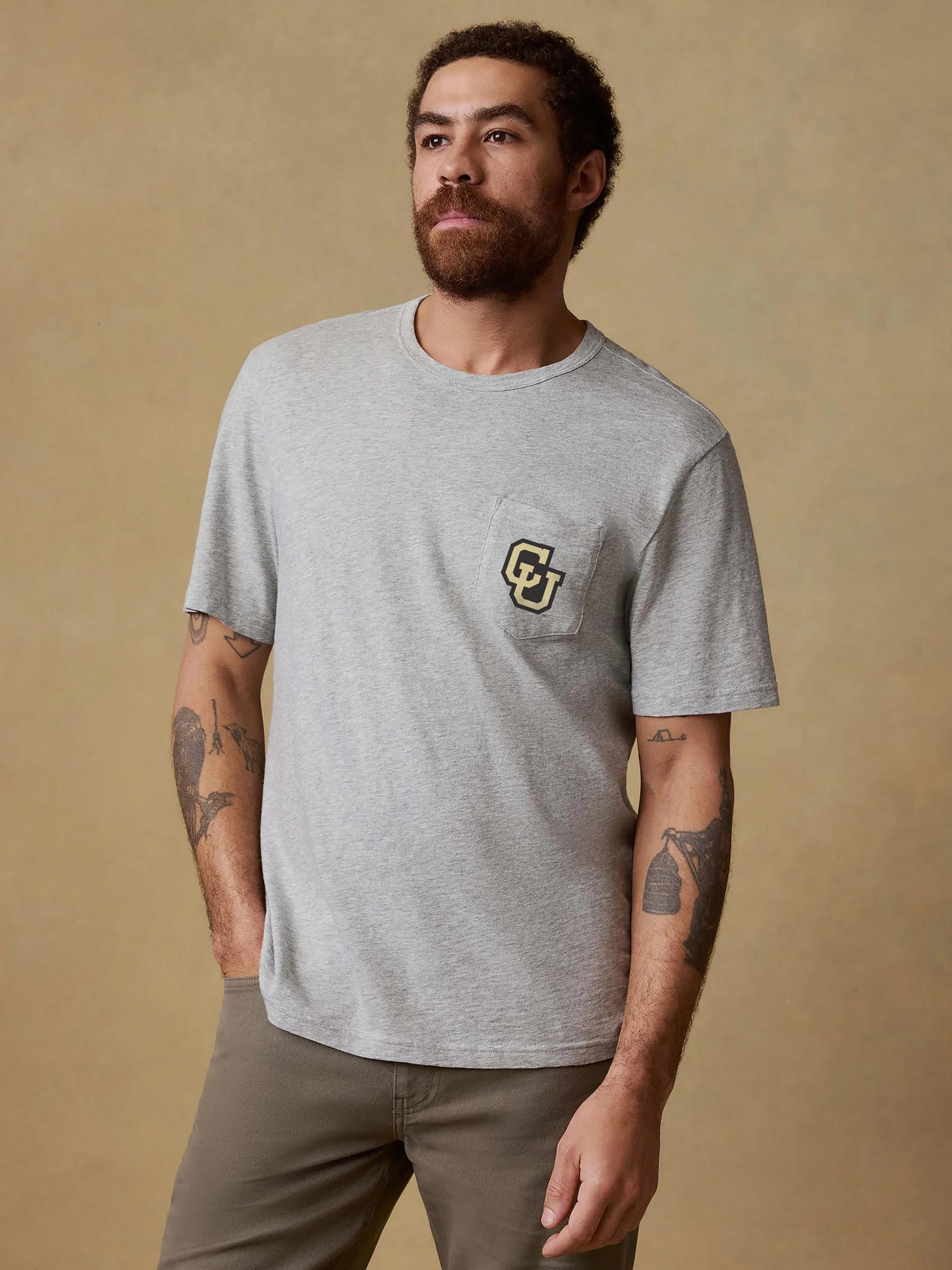 A man wearing a grey CU Boulder tee and brown pants, image 1 of 2