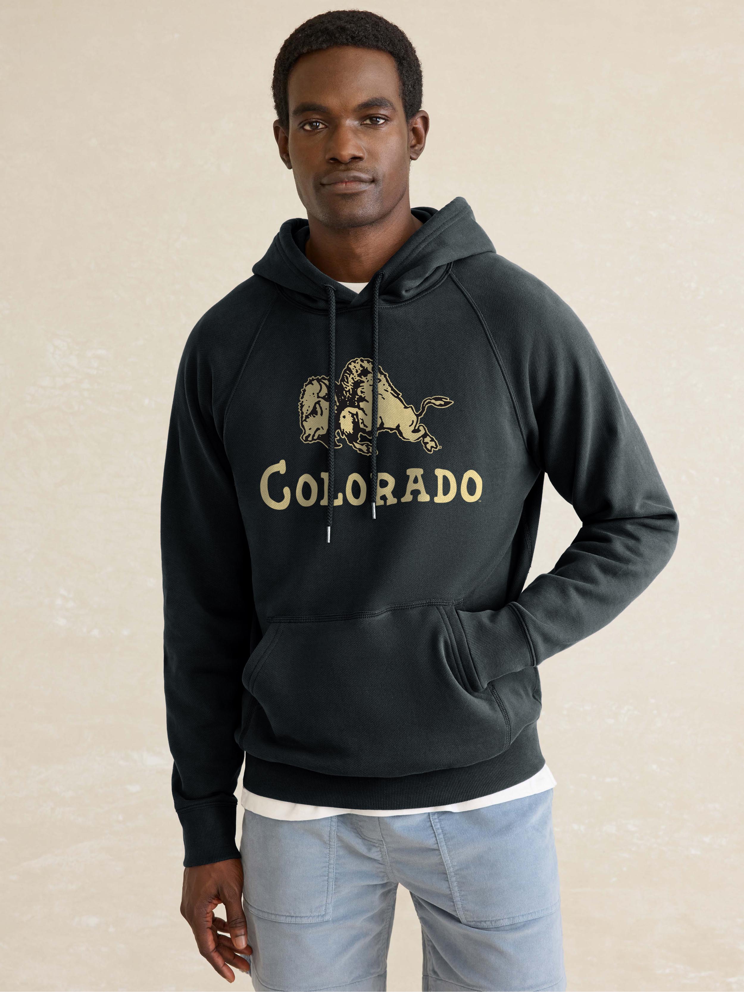 A man wearing a black CU Boulder hoodie and blue pants