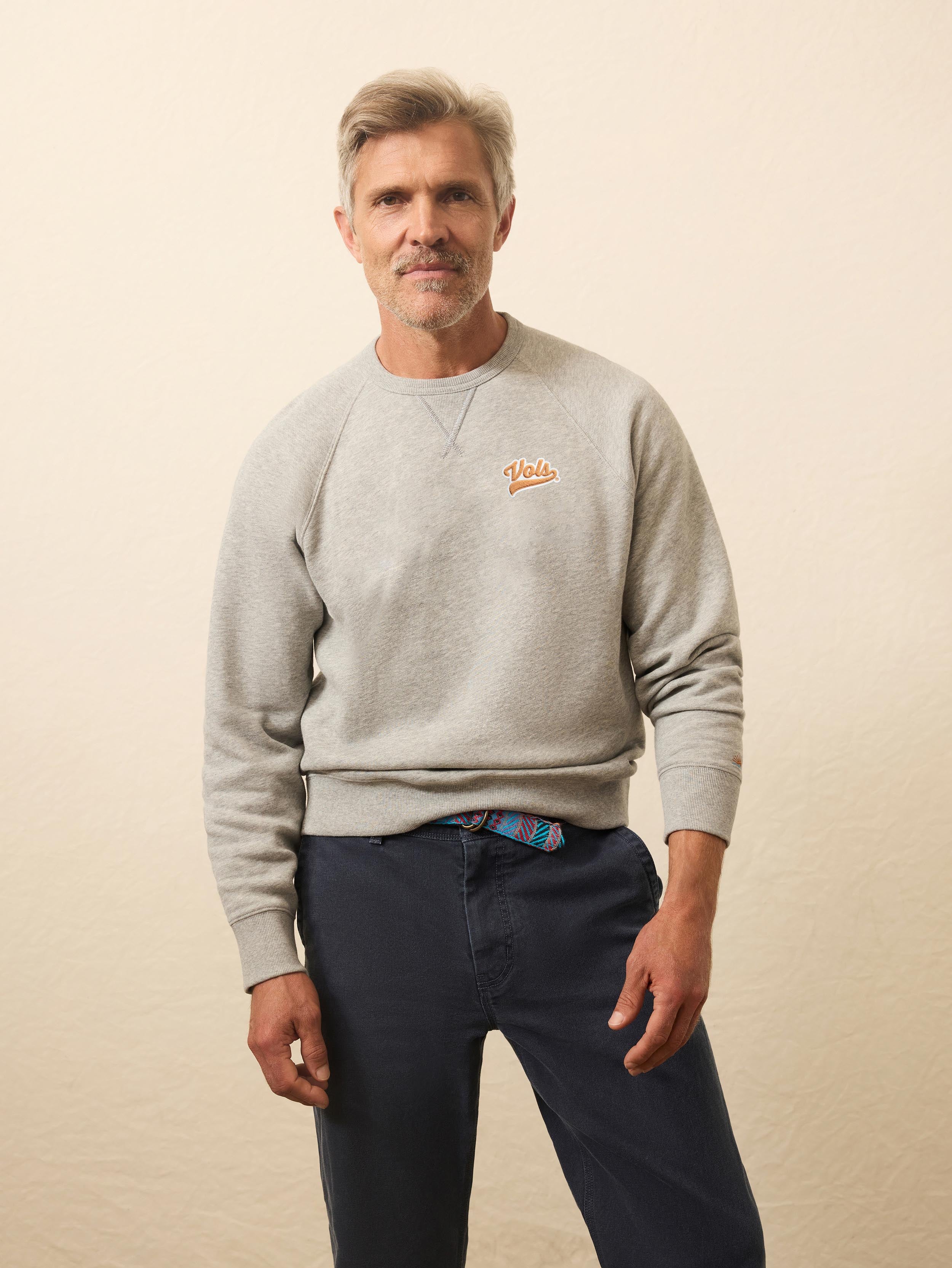 A man wearing a grey University of Tennessee crewneck and blue pants