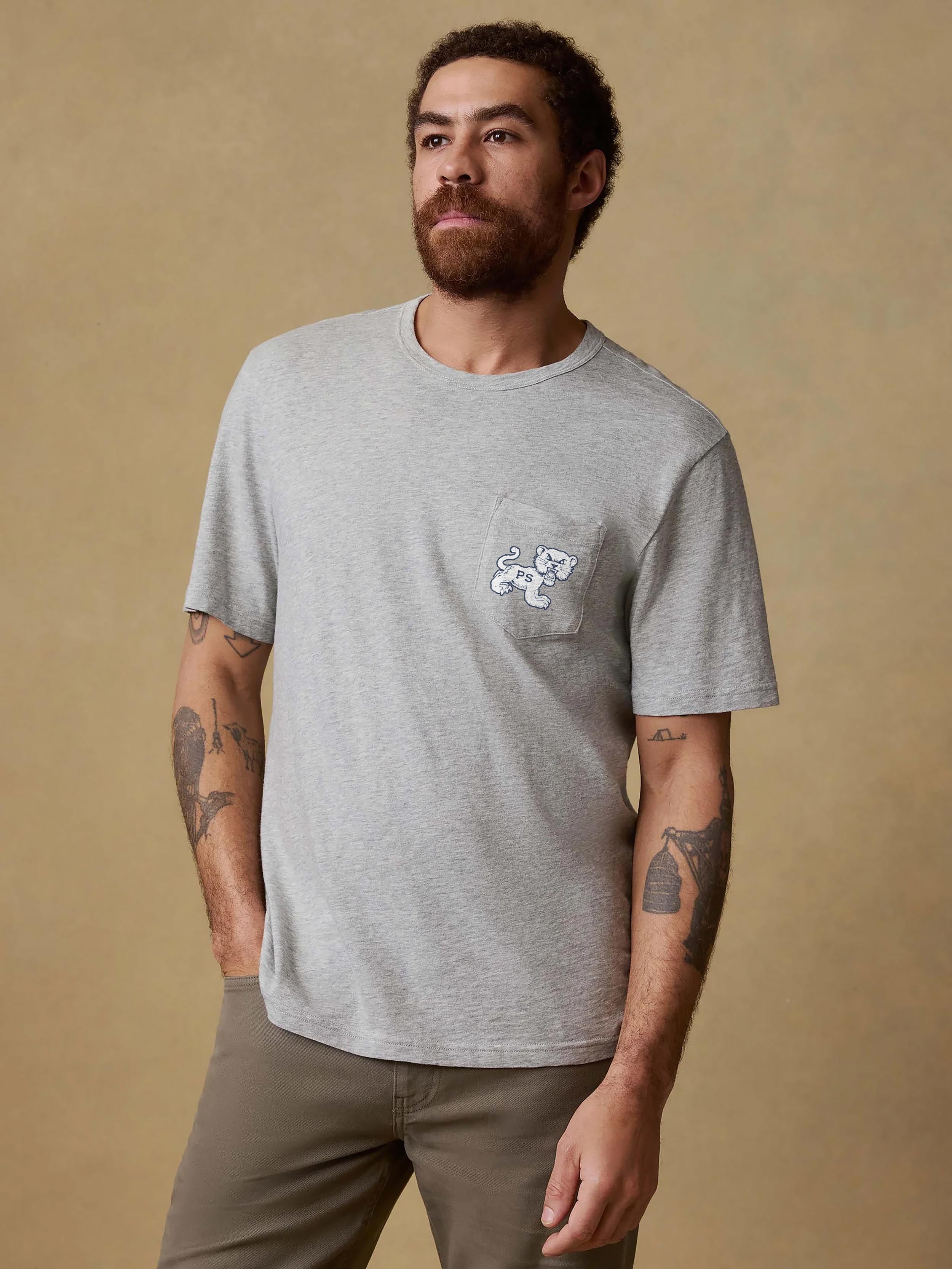 A man wearing a grey Penn State tee and brown pants