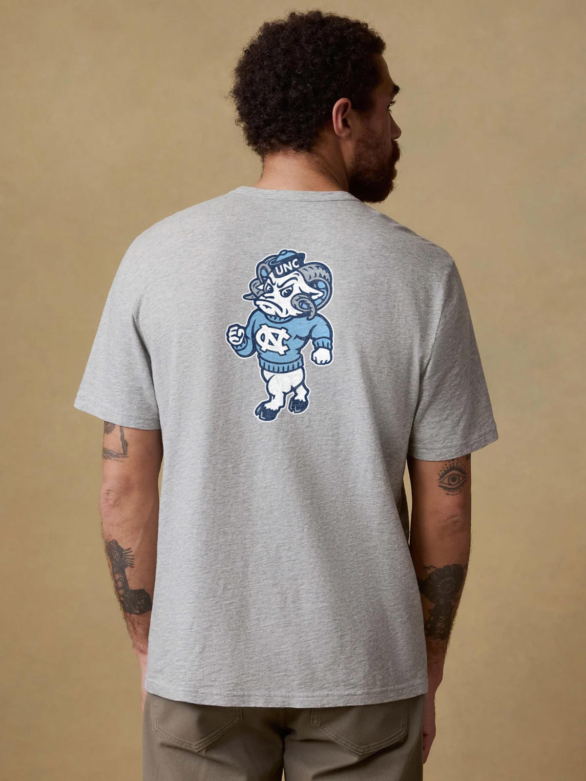 A man viewed from behind wearing a grey University of North Carolina and brown pants, image 2 of 2