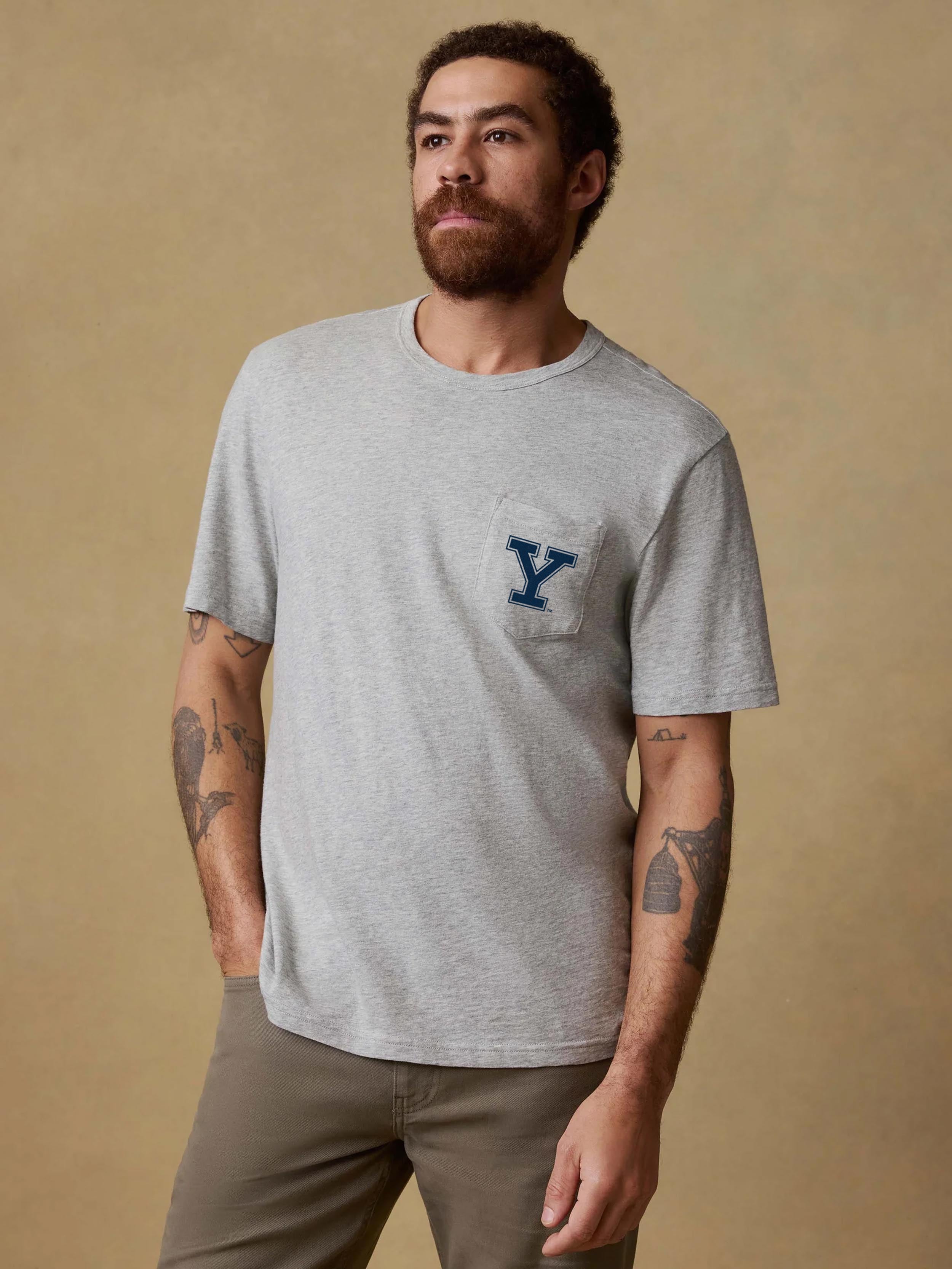 A man wearing a grey Yale tee and brown pants