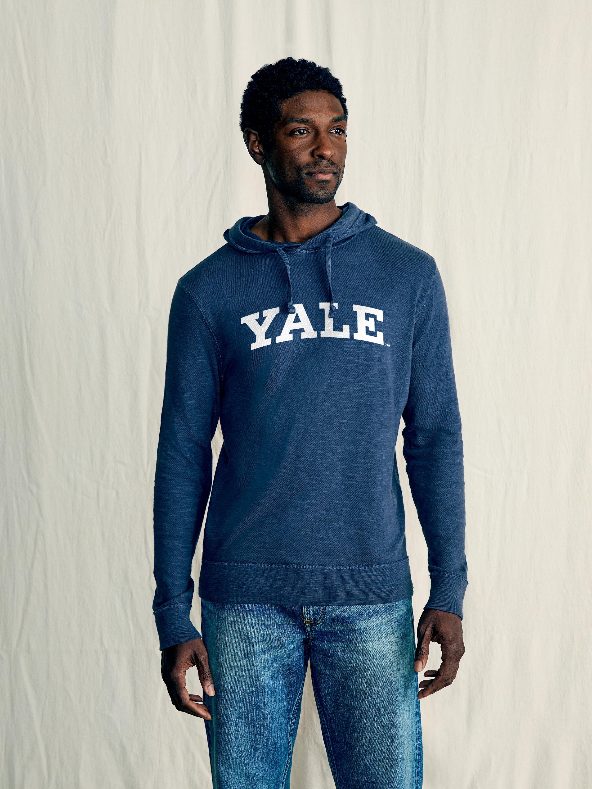 A man wearing a blue Yale hoodie and blue jeans