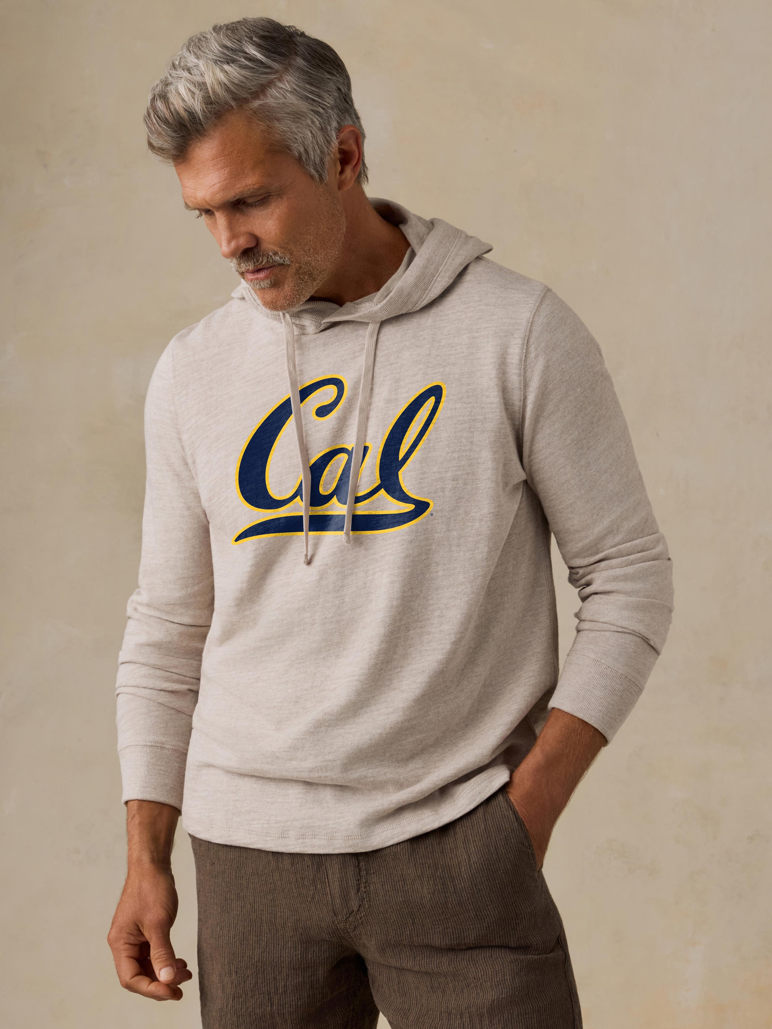 A man wearing a grey UC Berkeley hoodie and brown shorts