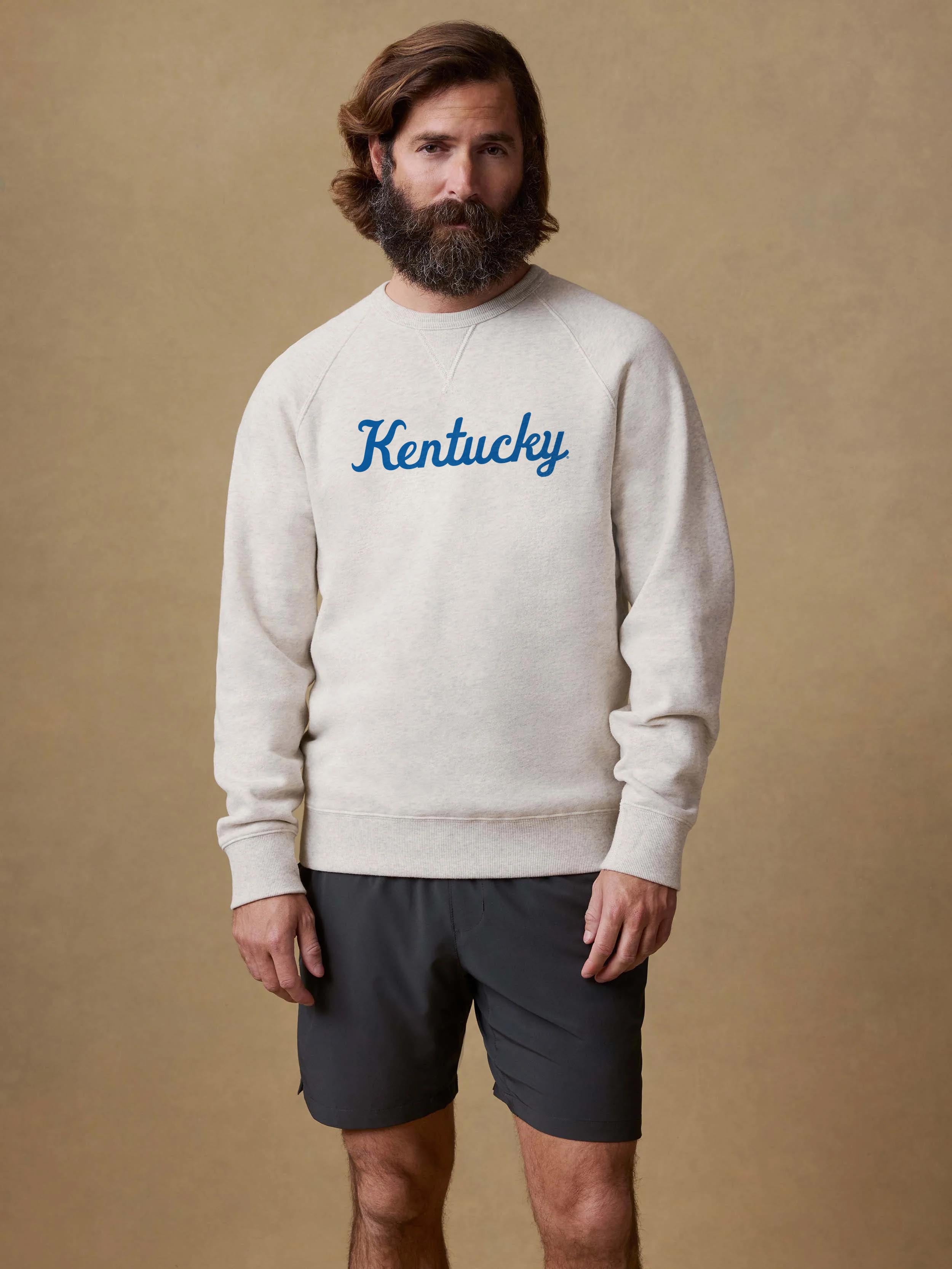A man wearing a grey University of Kentucky crewneck and black shorts