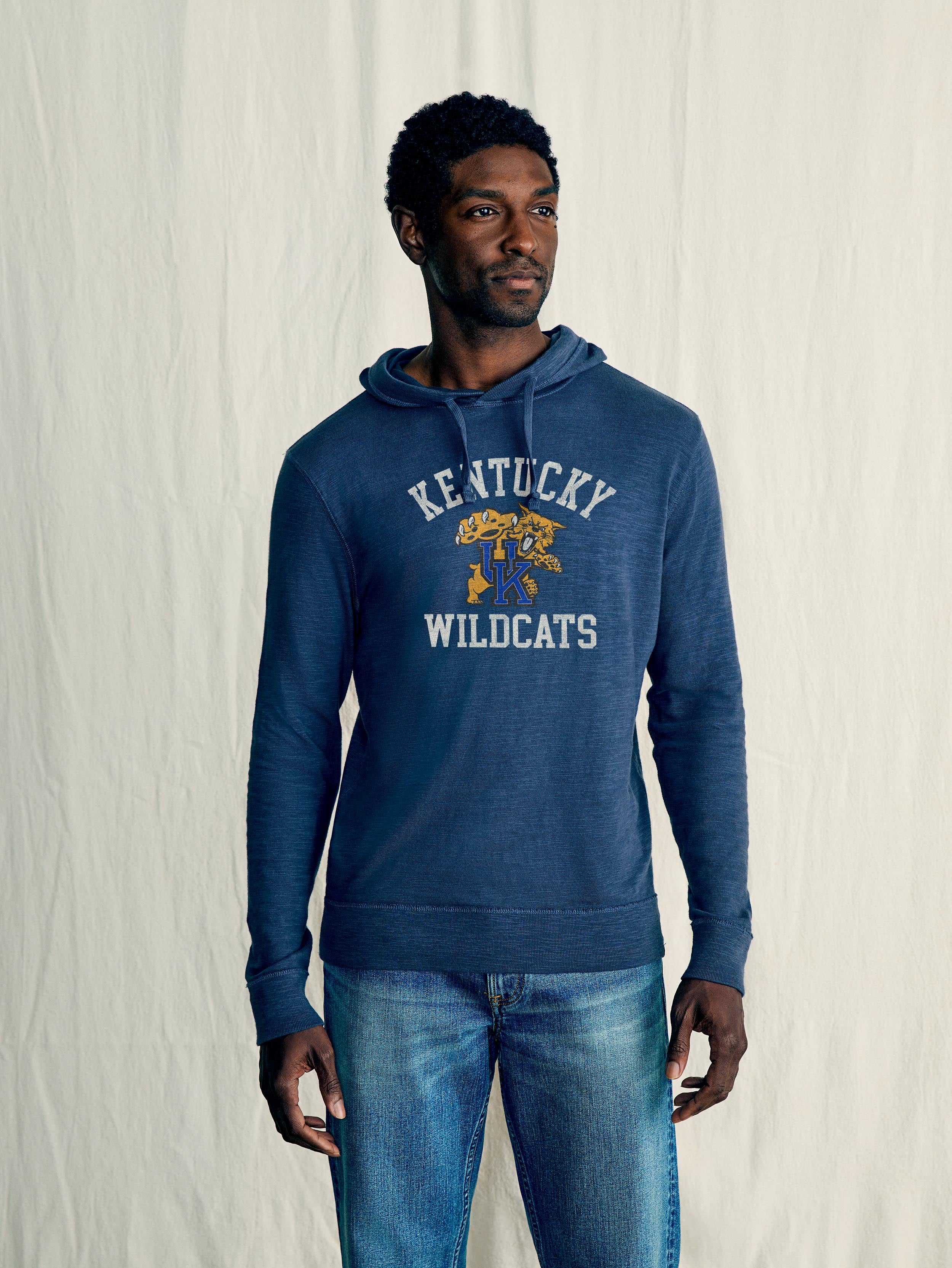 A man wearing a blue University of Kentucky hoodie and blue jeans