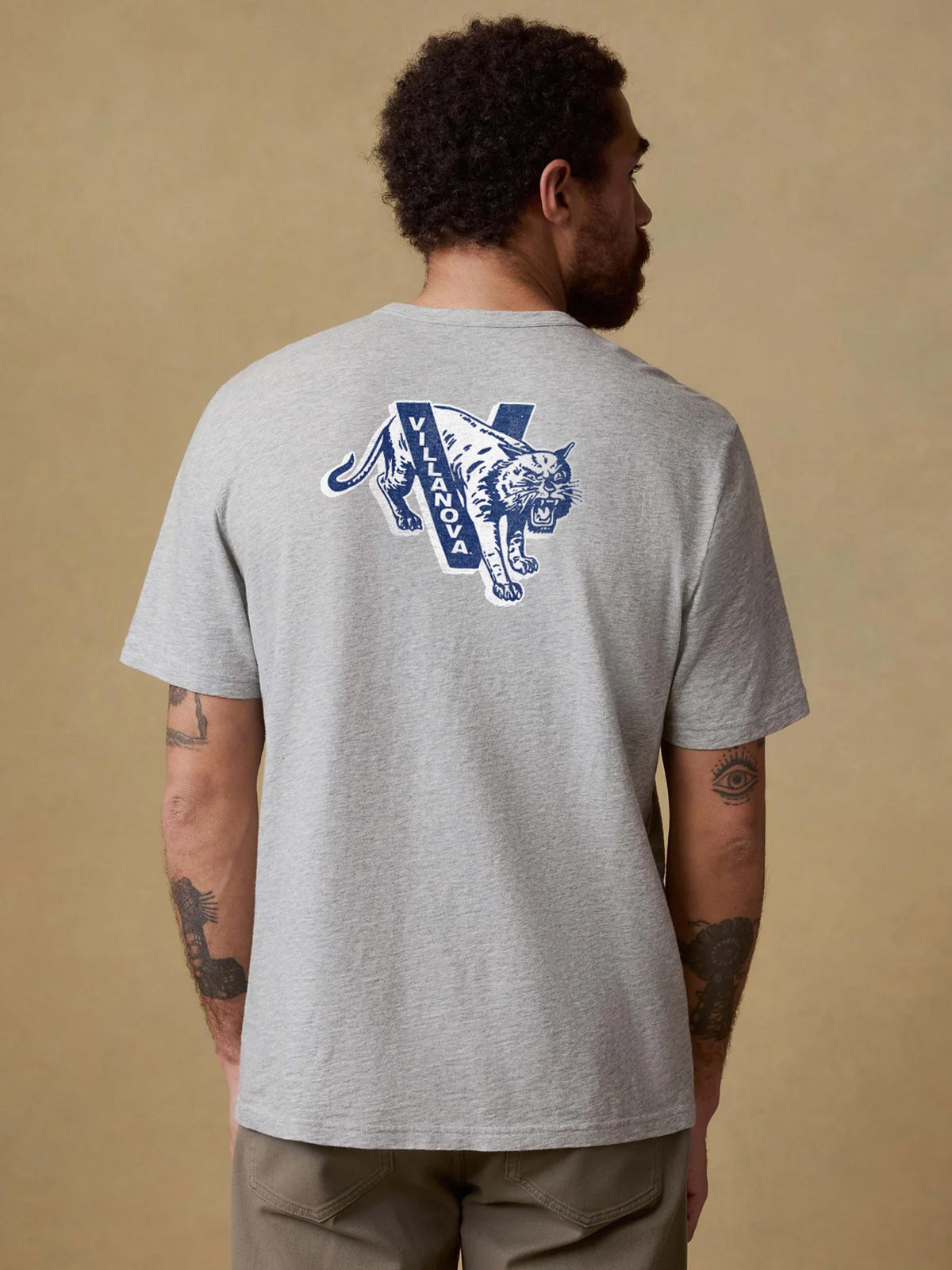 A man viewed from behind wearing a grey Villanova pocket tee and brown pants, image 2 of 2