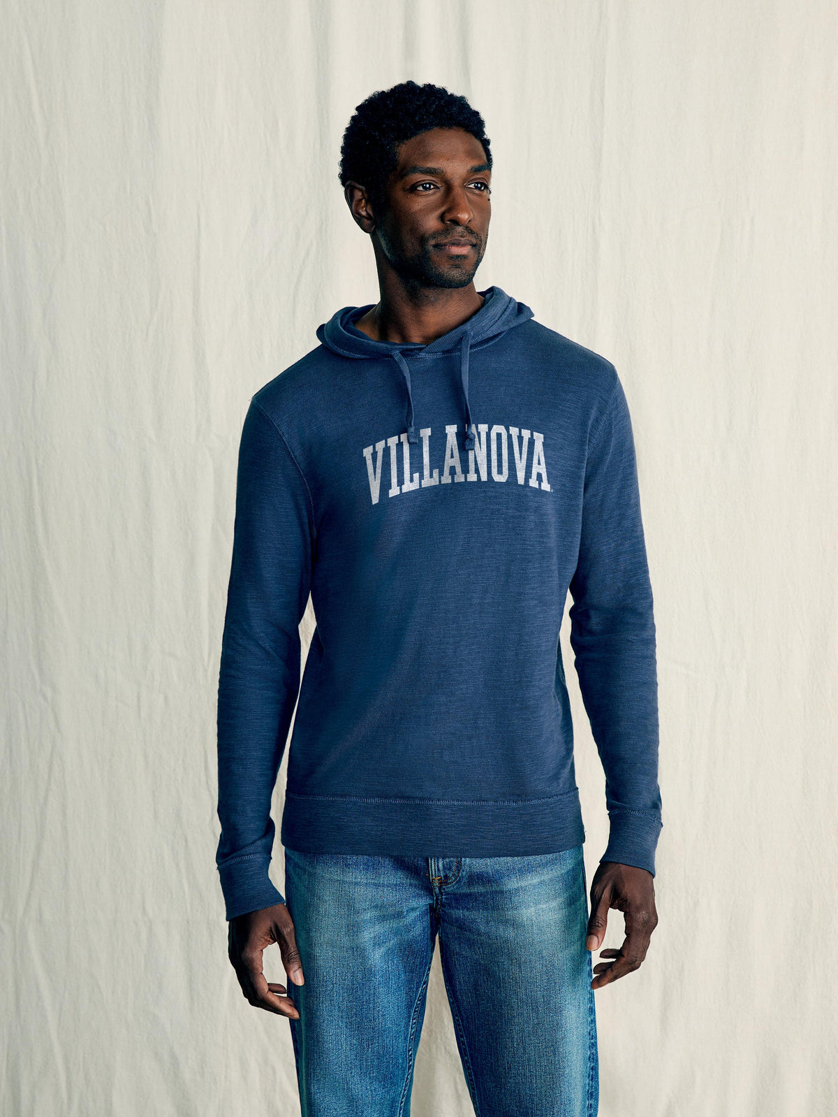 A man wearing a blue Villanova hoodie and blue jeans, image 1 of 1