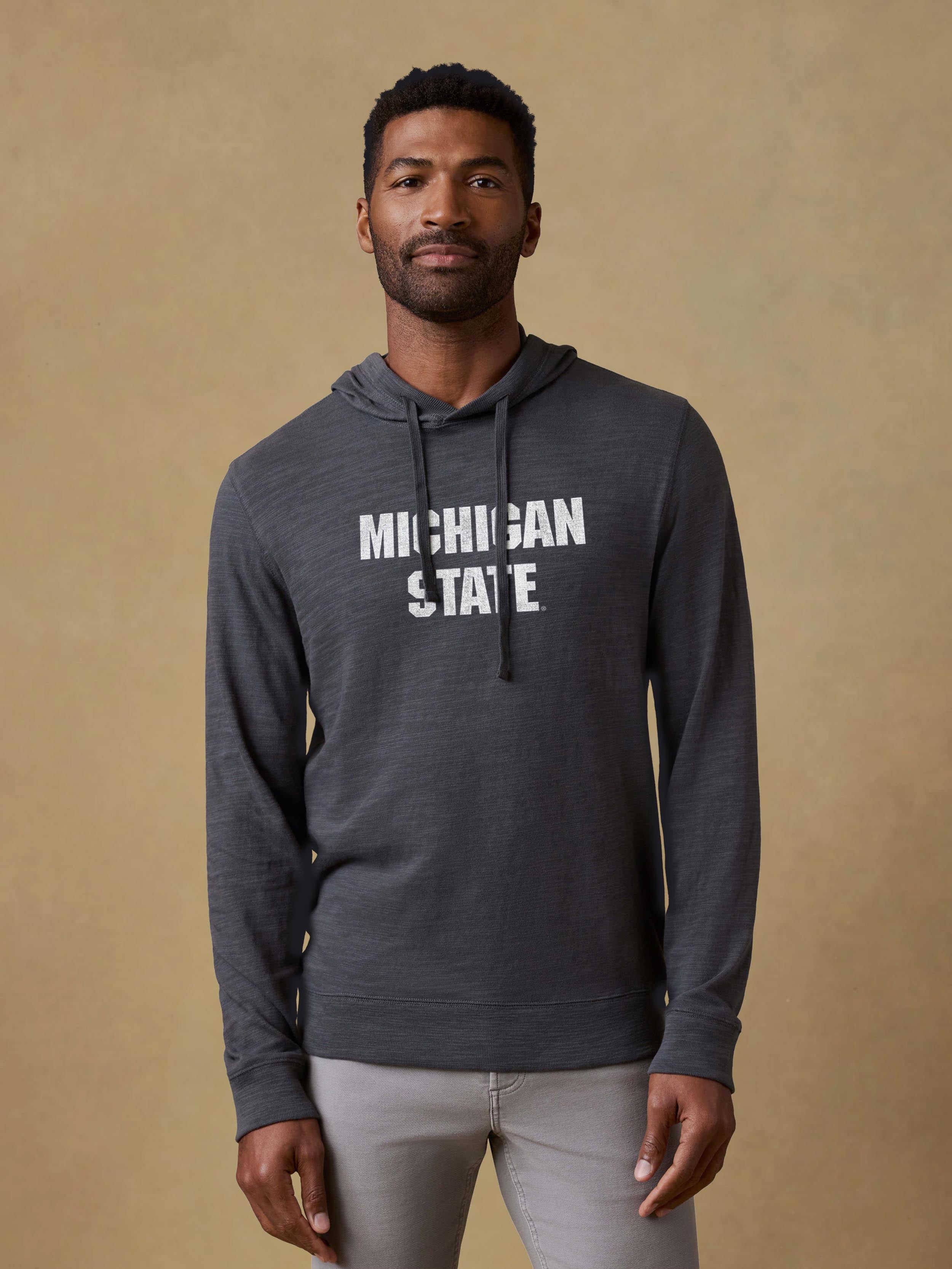 A man wearing a grey Michigan State hoodie and light grey pants
