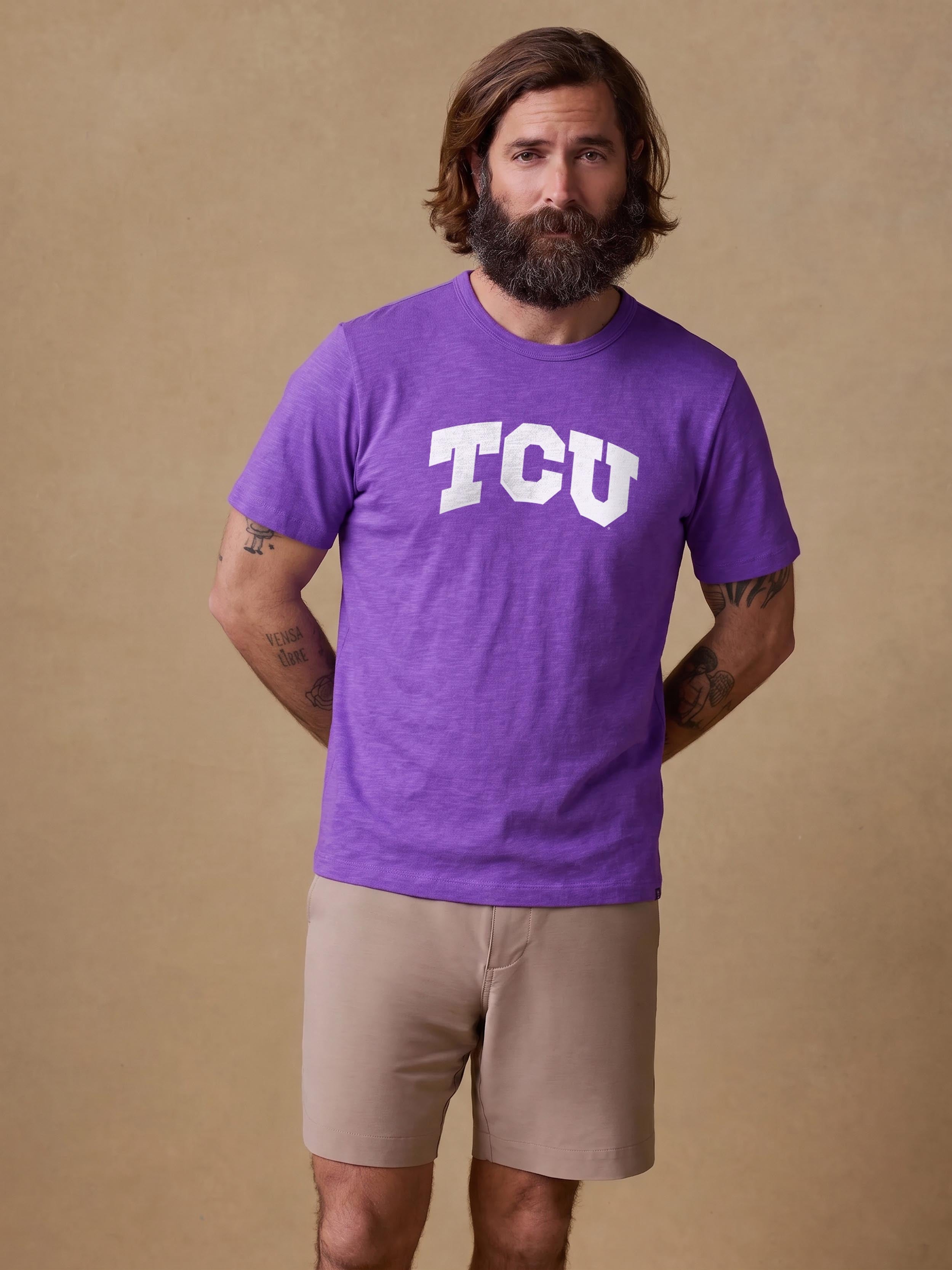 A man wearing a purple TCU tee and beige shorts