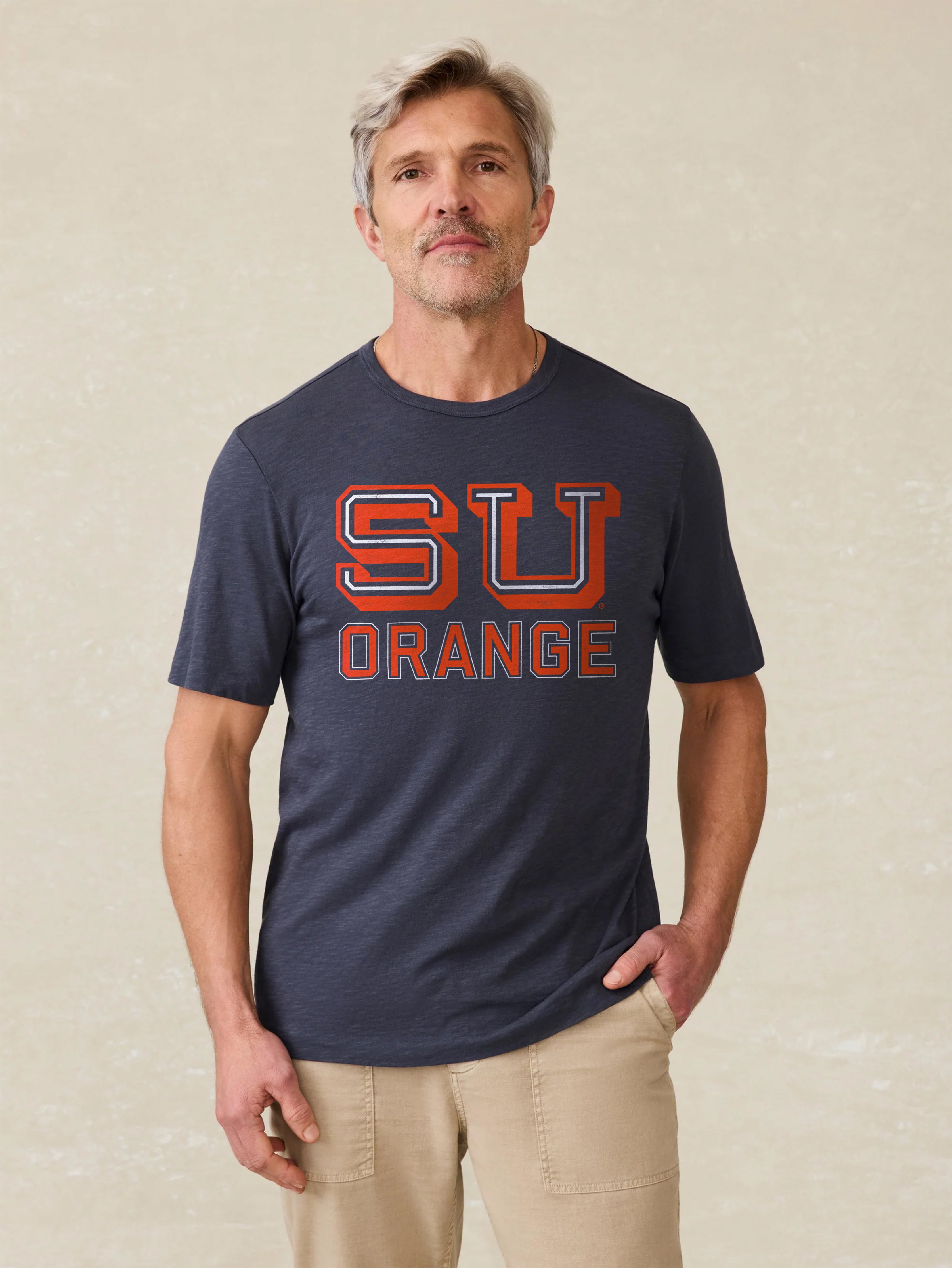 Man wearing a navy t-shirt with a Syracuse University graphic on the center front against a beige background