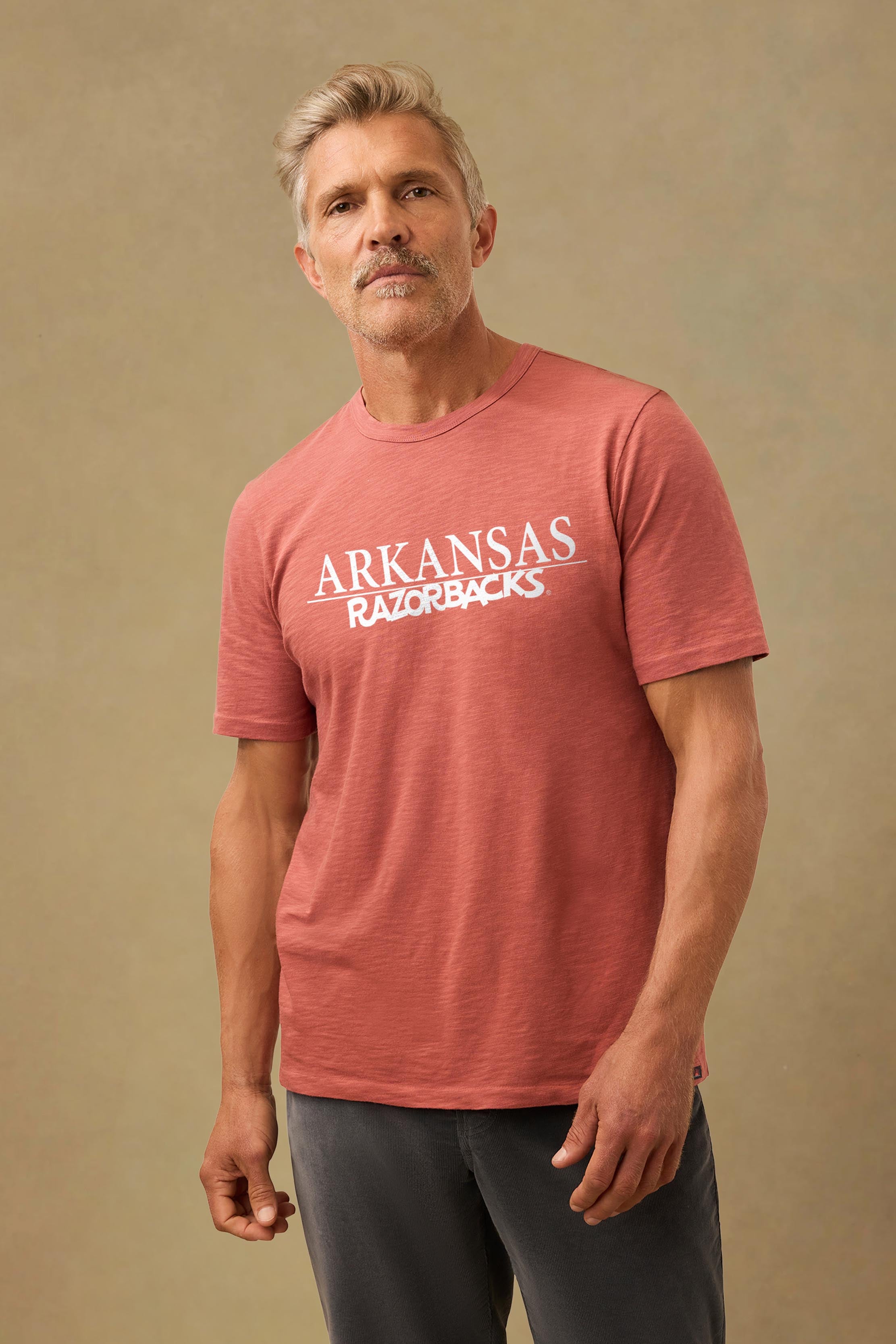 A man wearing a red University of Arkansas tee and black pants