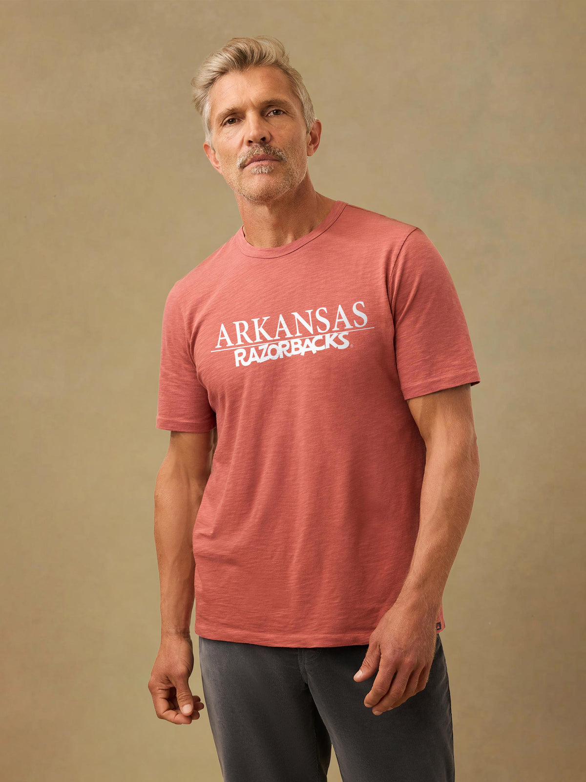 A man wearing a red University of Arkansas tee and black pants, image 1 of 1