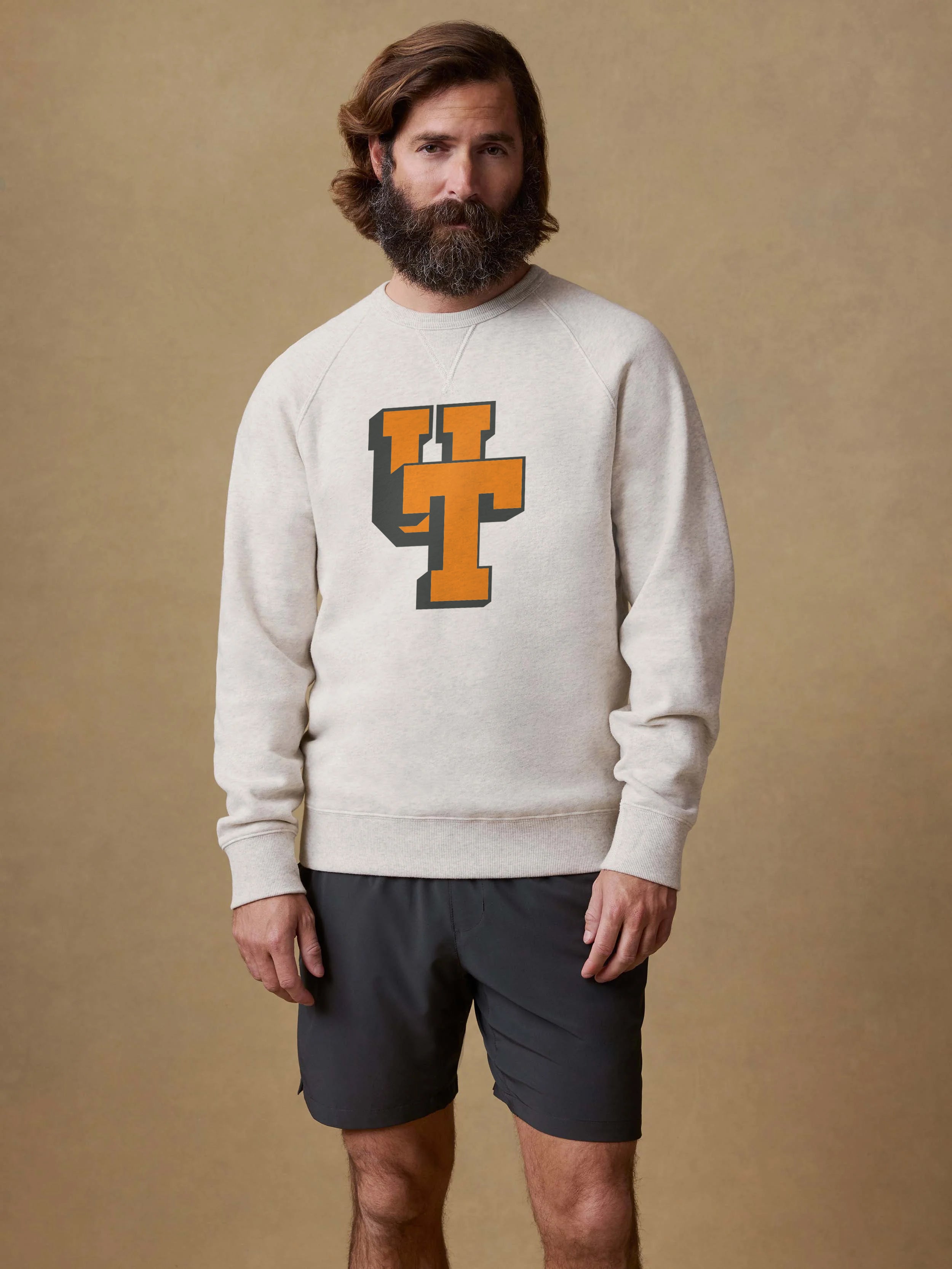 Man wearing an ivory heather sweatshirt with a University of Tennessee logo on the center from against a beige background