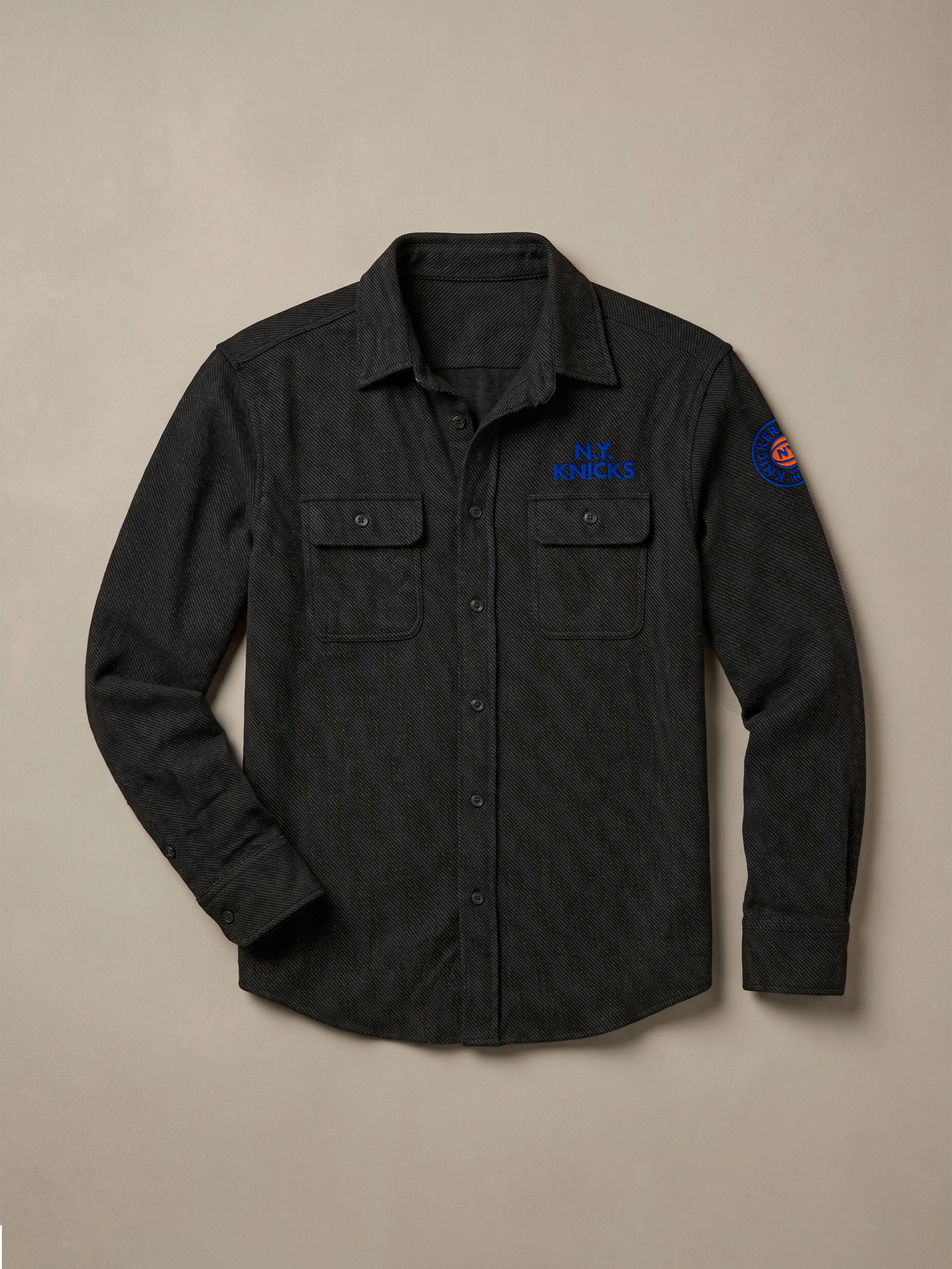 Black shirt with embroidered NY Knicks graphics against a beige background