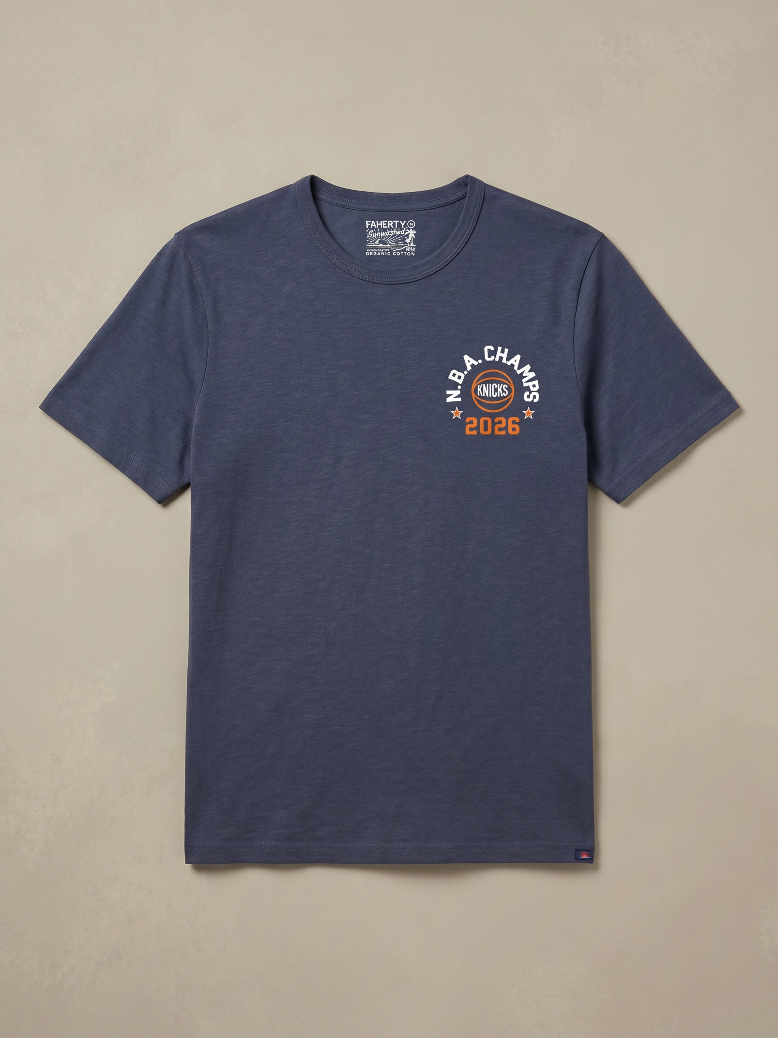 Navy blue t-shirt with a NY Knicks graphic logo on the left chest against a beige background