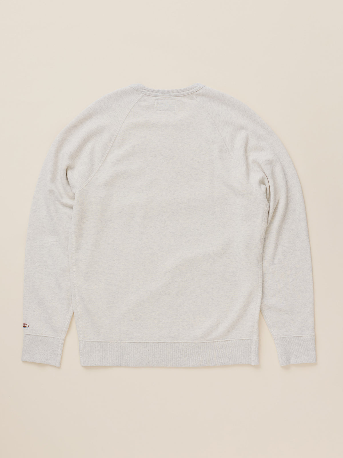 A light heather gray crewneck sweatshirt shown from the back, laid flat on a warm beige background., image 8 of 8