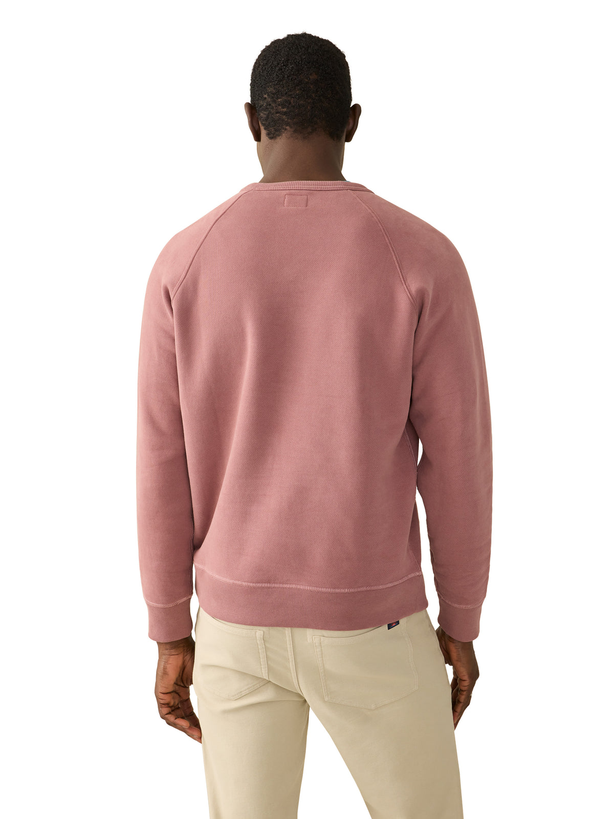 A man viewed from the back wearing a pink crewneck and beige pants, image 3 of 3