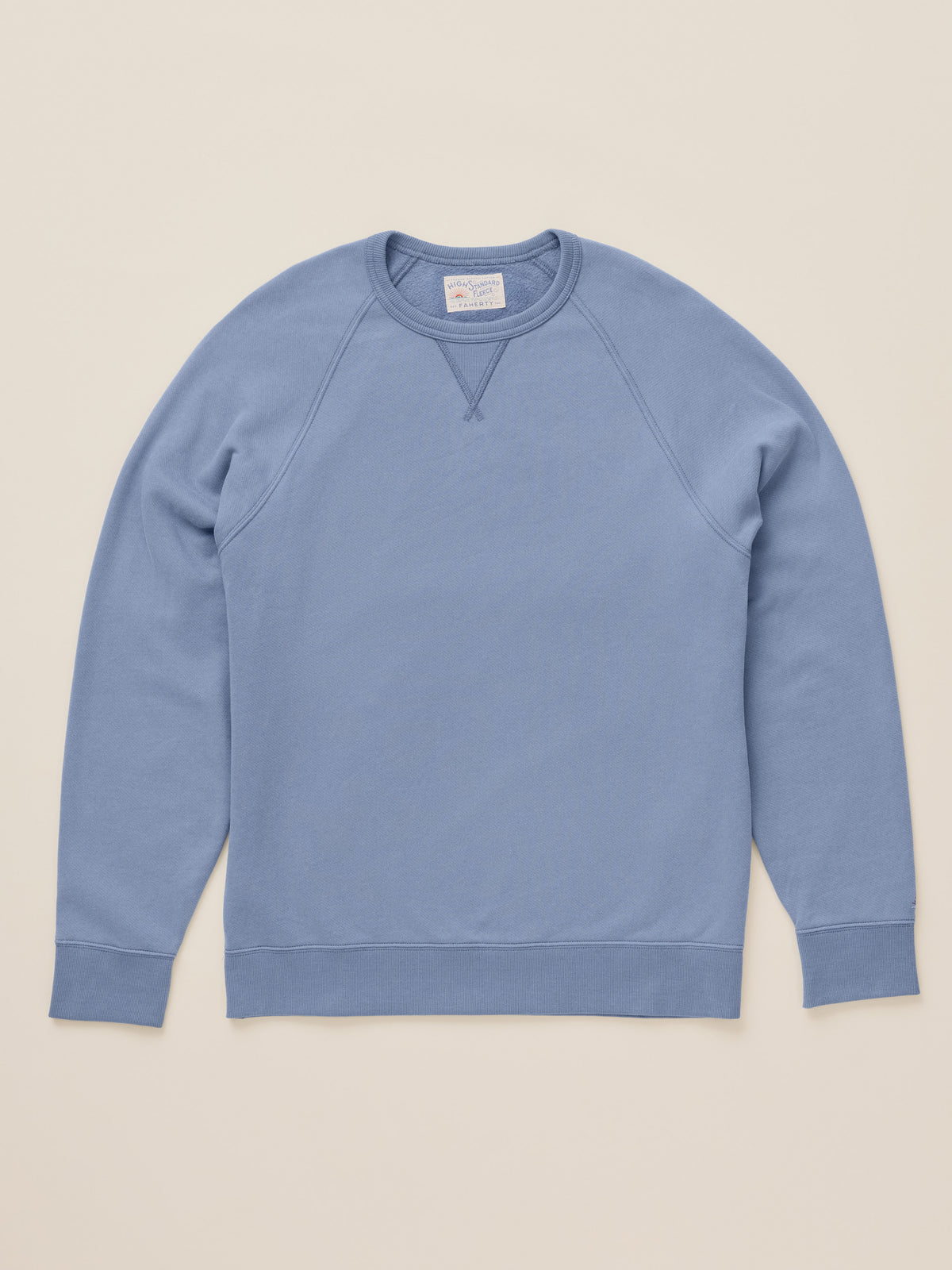 A light blue ribbed crewneck sweatshirt laid flat against a solid beige background., image 7 of 8