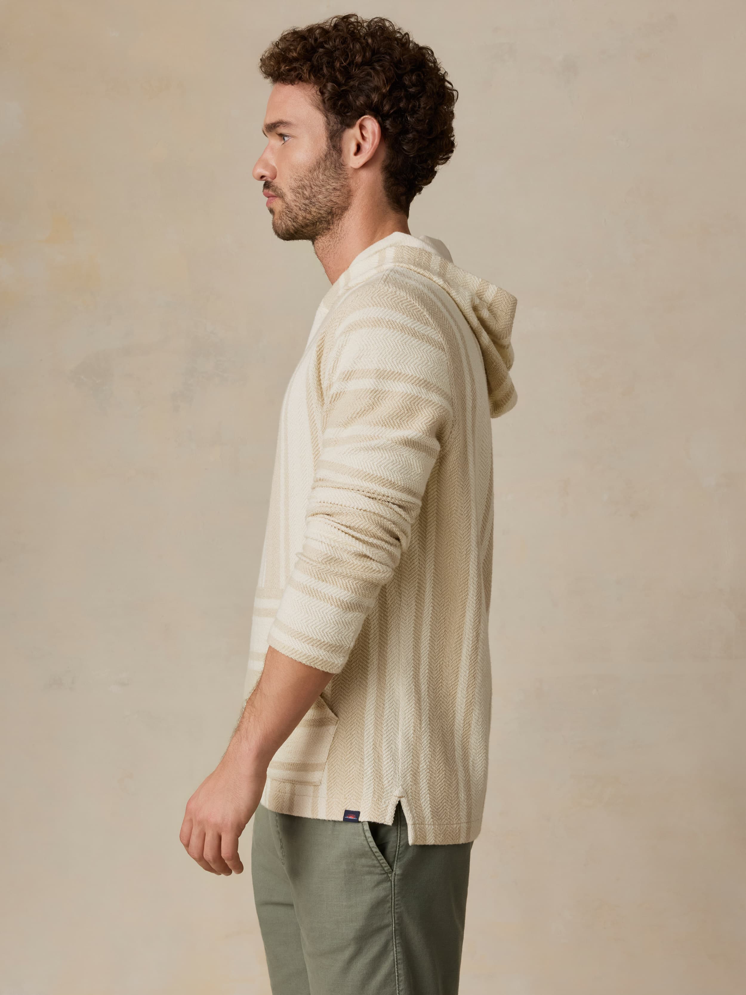 Man wearing a beige hooded jacket against a beige background