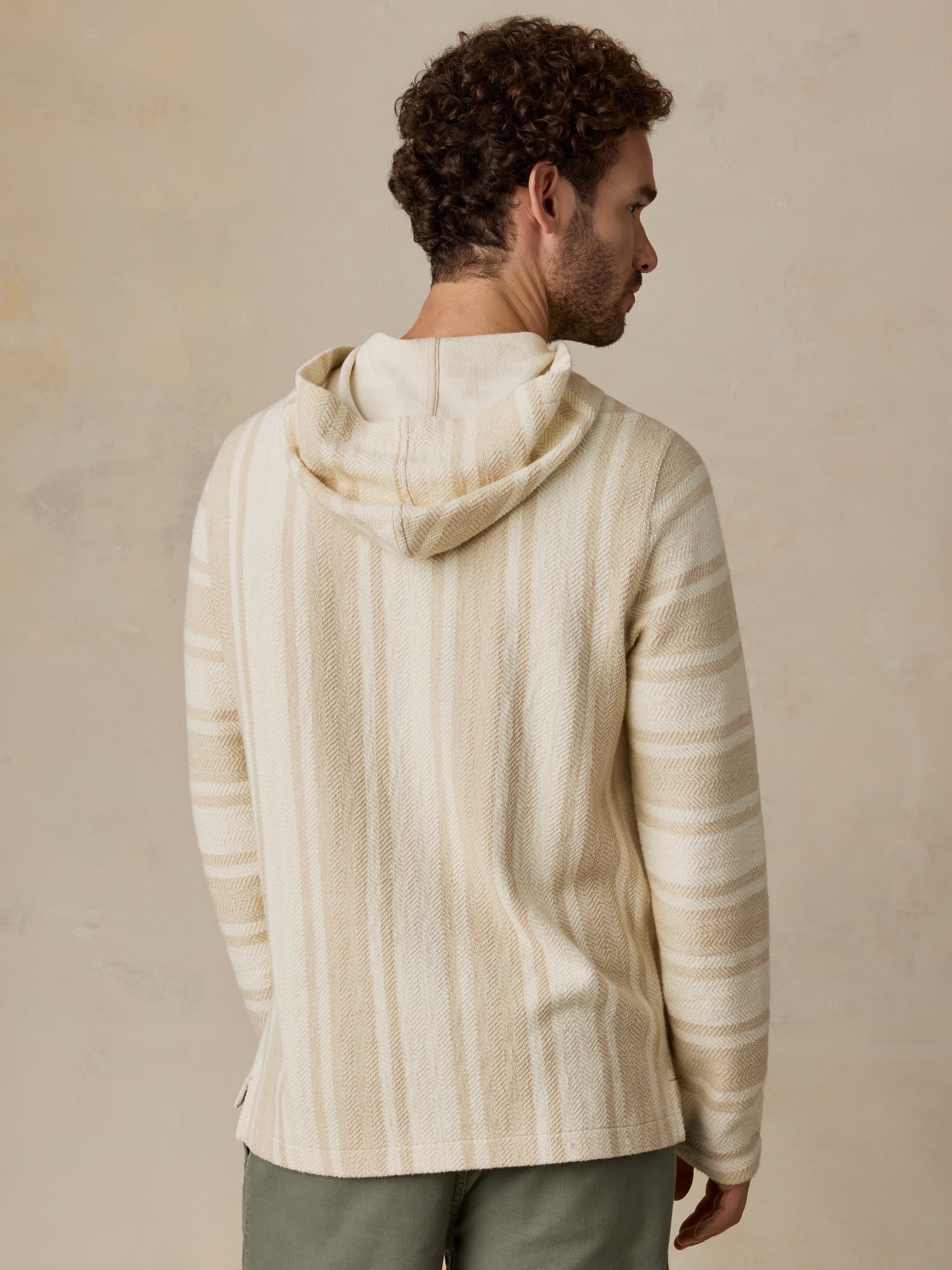 Man wearing a cream-colored striped hoodie against a beige background